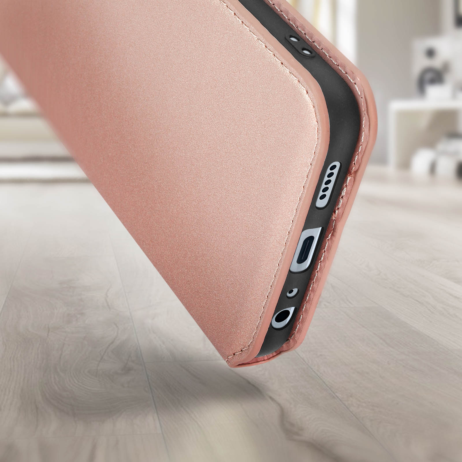 Roségoldfarbene Handyhülle auf verschwommenem Hintergrund. Die Hülle umschließt das Telefon.
