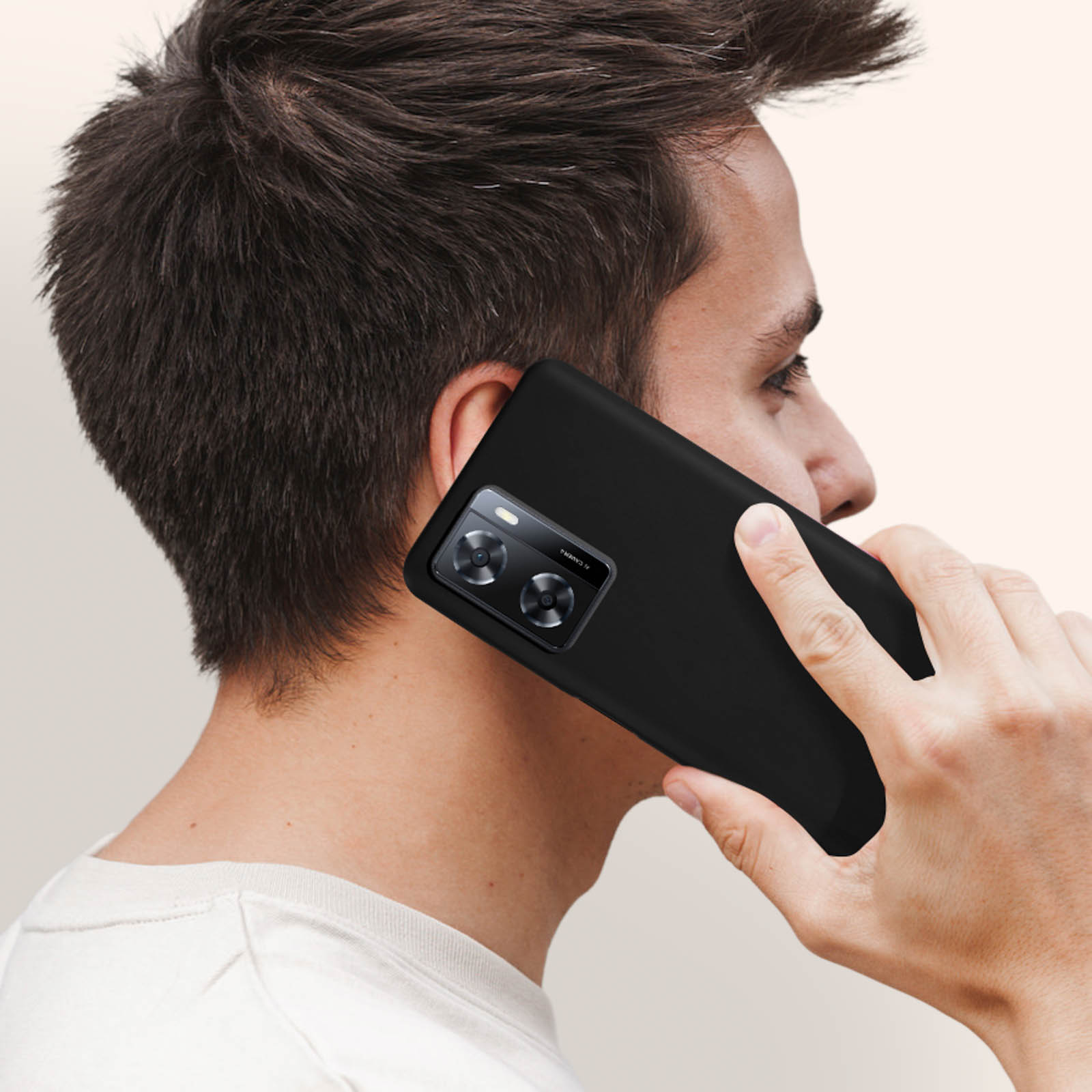 Un uomo che tiene un telefono nero all'orecchio. Il telefono ha doppie fotocamere.