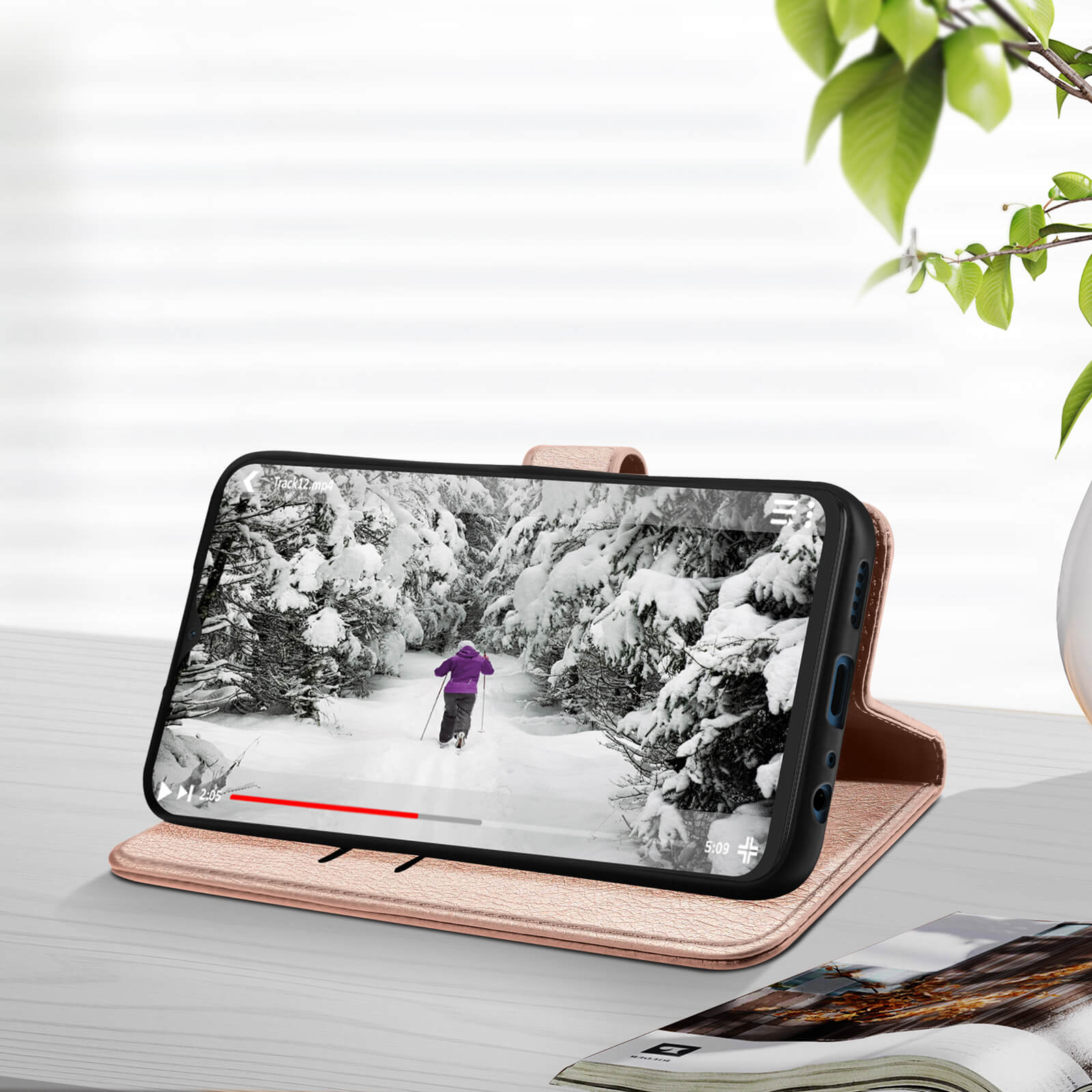 Ein Telefon, das ein Video einer schneebedeckten Landschaft zeigt, auf einer roségoldenen Handyhülle platziert.
