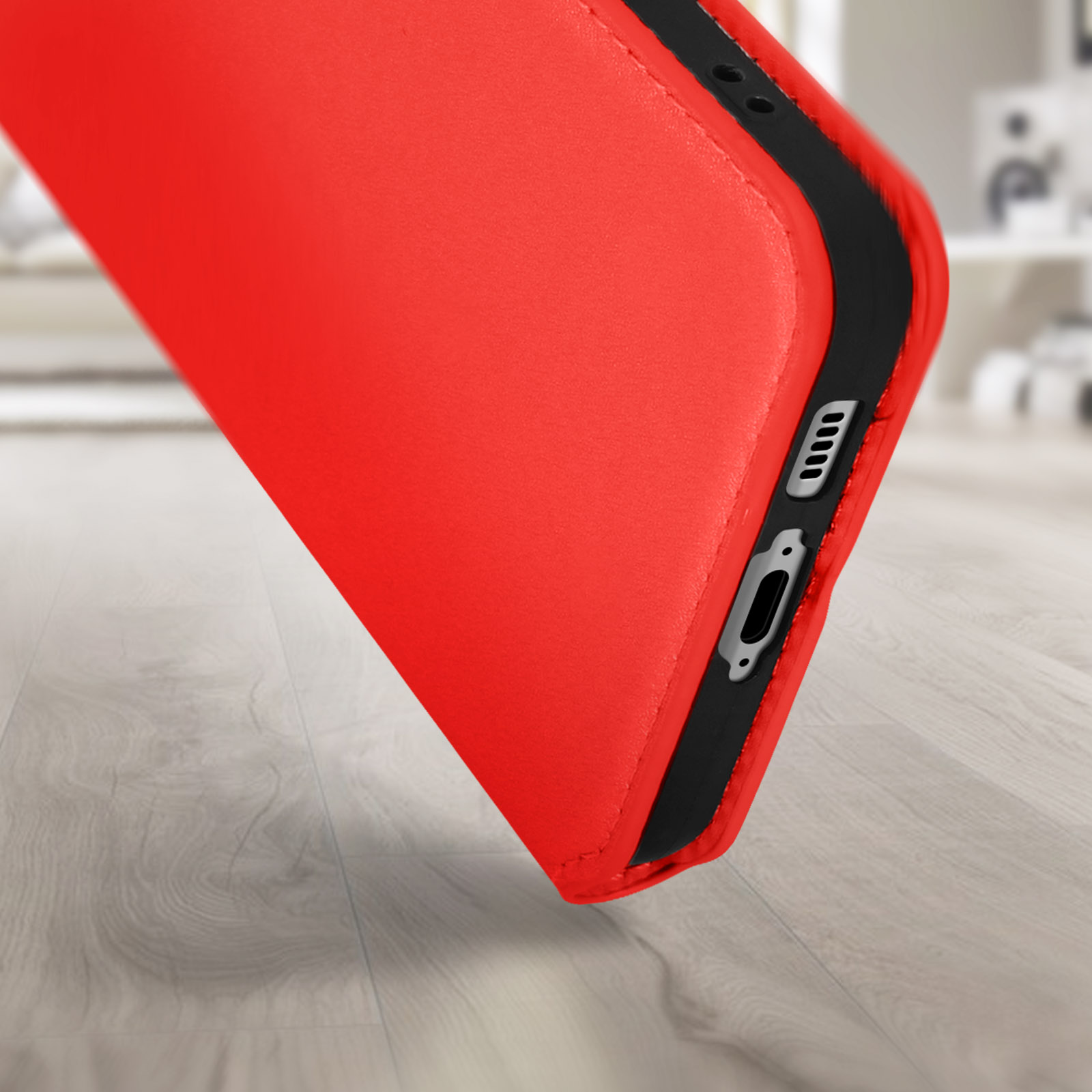 Una custodia per telefono rossa, con bordo nero, è leggermente inclinata. La custodia è appoggiata su una superficie di legno.