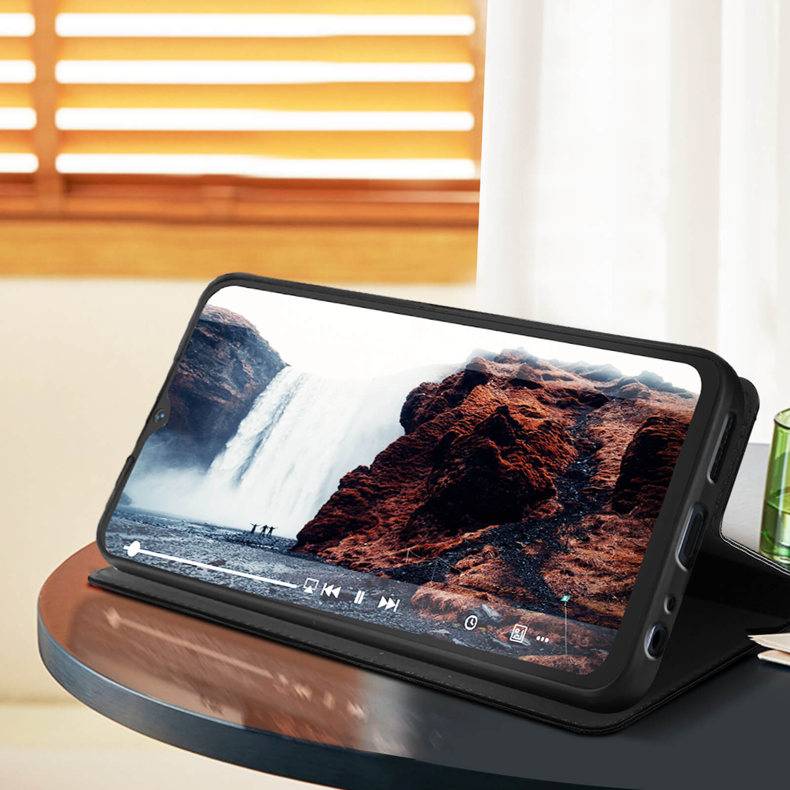 Handyhülle mit Telefon, das ein Video eines Wasserfalls zeigt. Auf einem Tisch.
