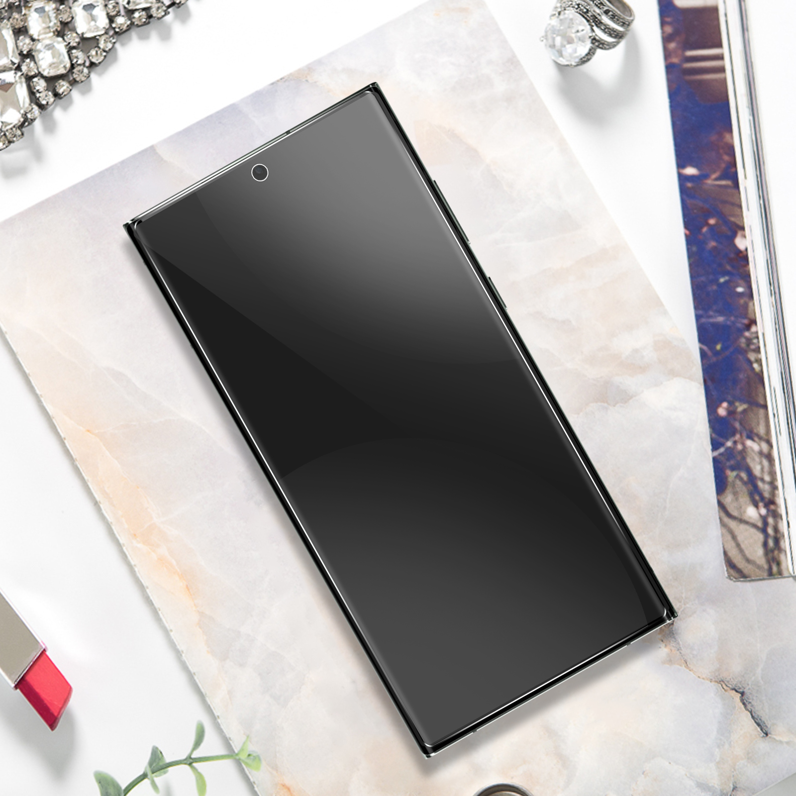 Uno schermo del telefono nero con un anello d'argento. Su una superficie di marmo con gioielli.