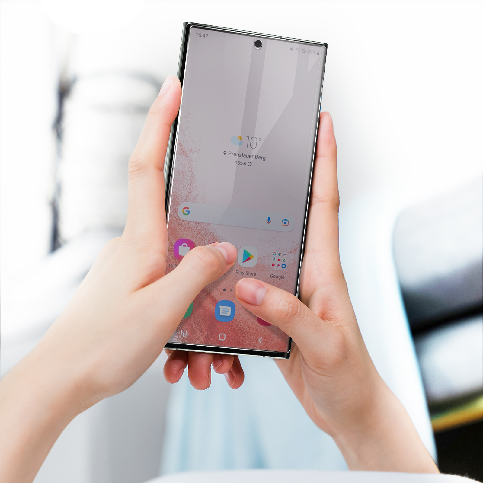 Mani che tengono un telefono che mostra la schermata iniziale. Lo sfondo è sfocato.