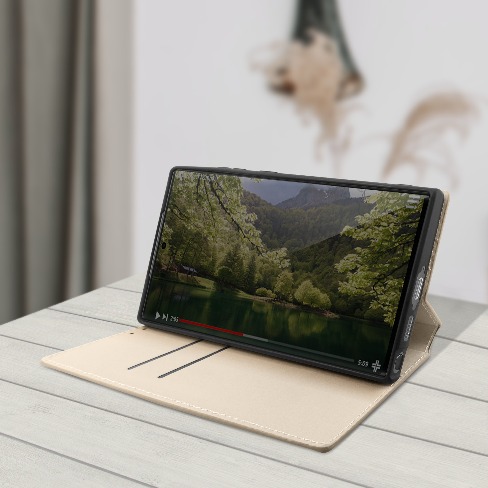Telefoon in een hoes, met een video van een natuurscène, op een beige oppervlak.