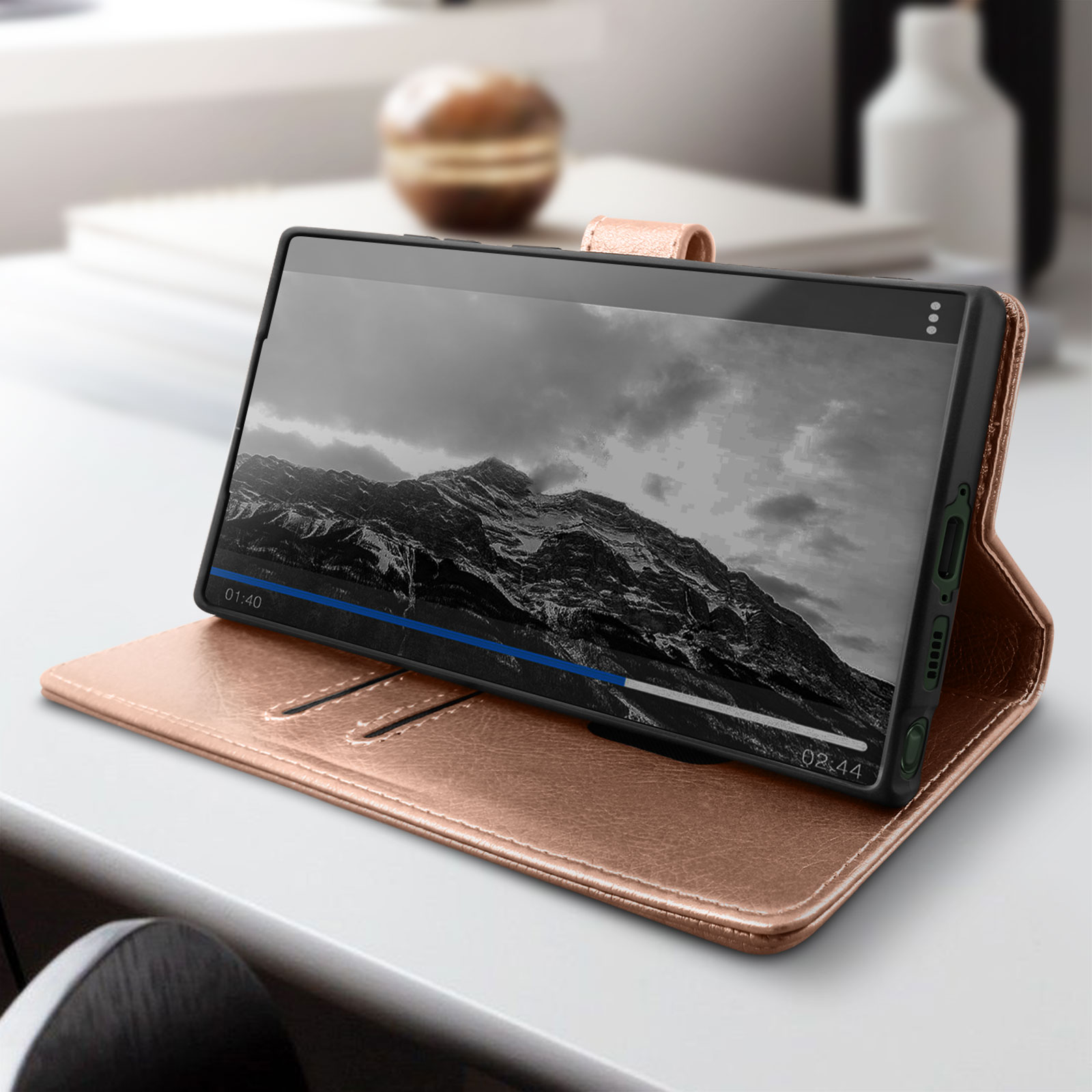 Telefoon in een roségouden hoes, met een video op een witte tafel, met een vage achtergrond.