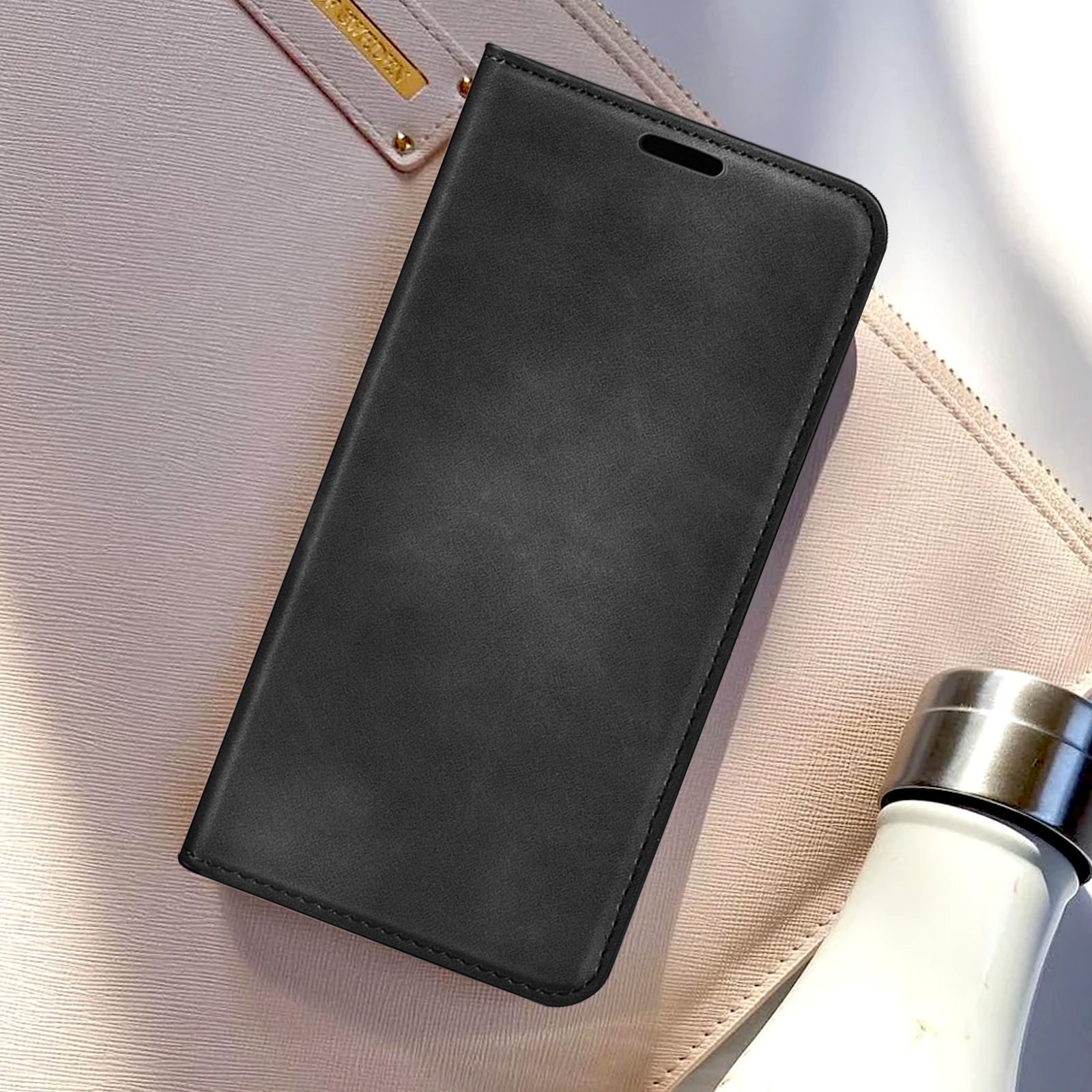 Een zwarte telefoonhoes, gesloten, op een beige oppervlak. Een witte waterfles staat op de achtergrond.