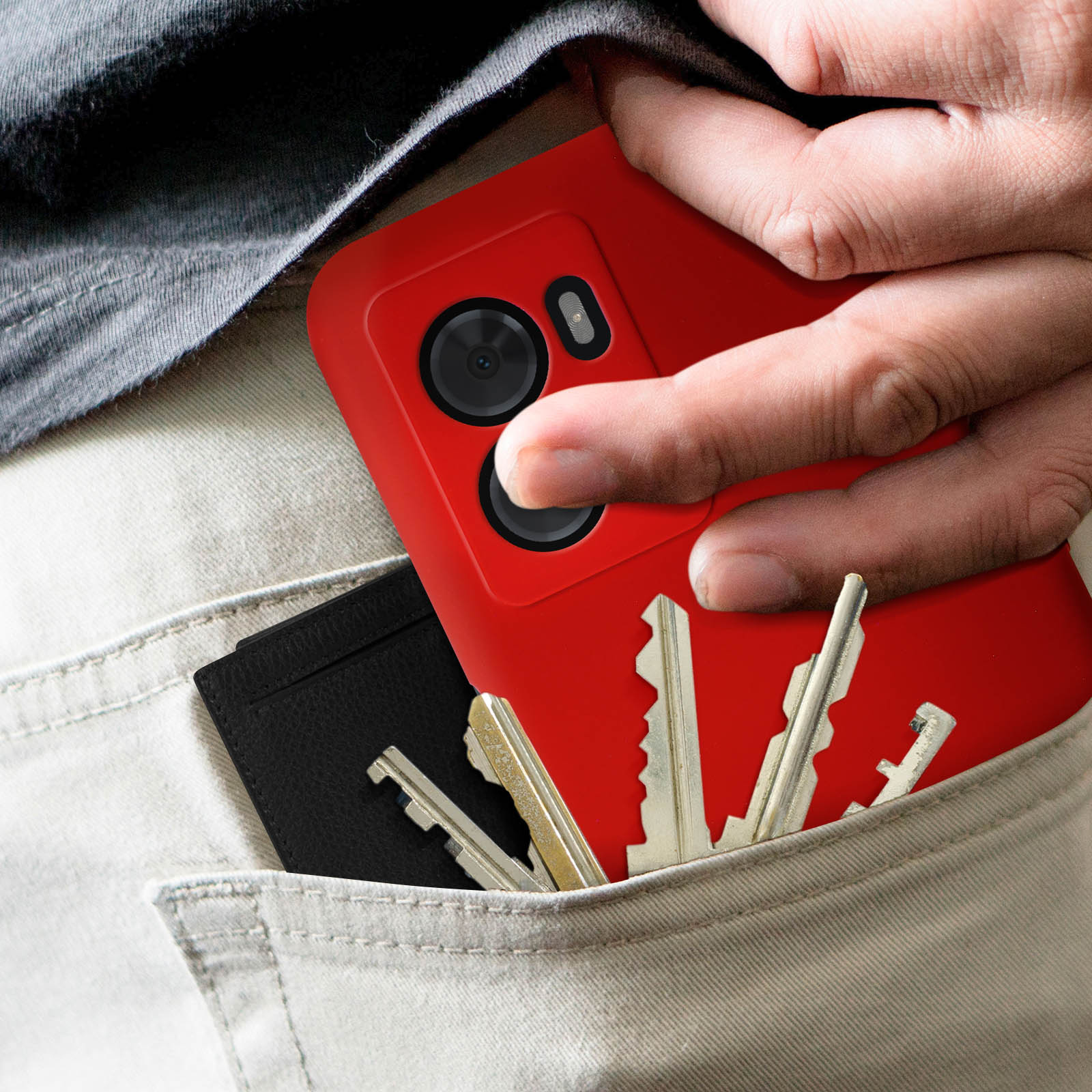 Una mano in tasca con chiavi e un portacarte nero. Un telefono rosso in tasca.