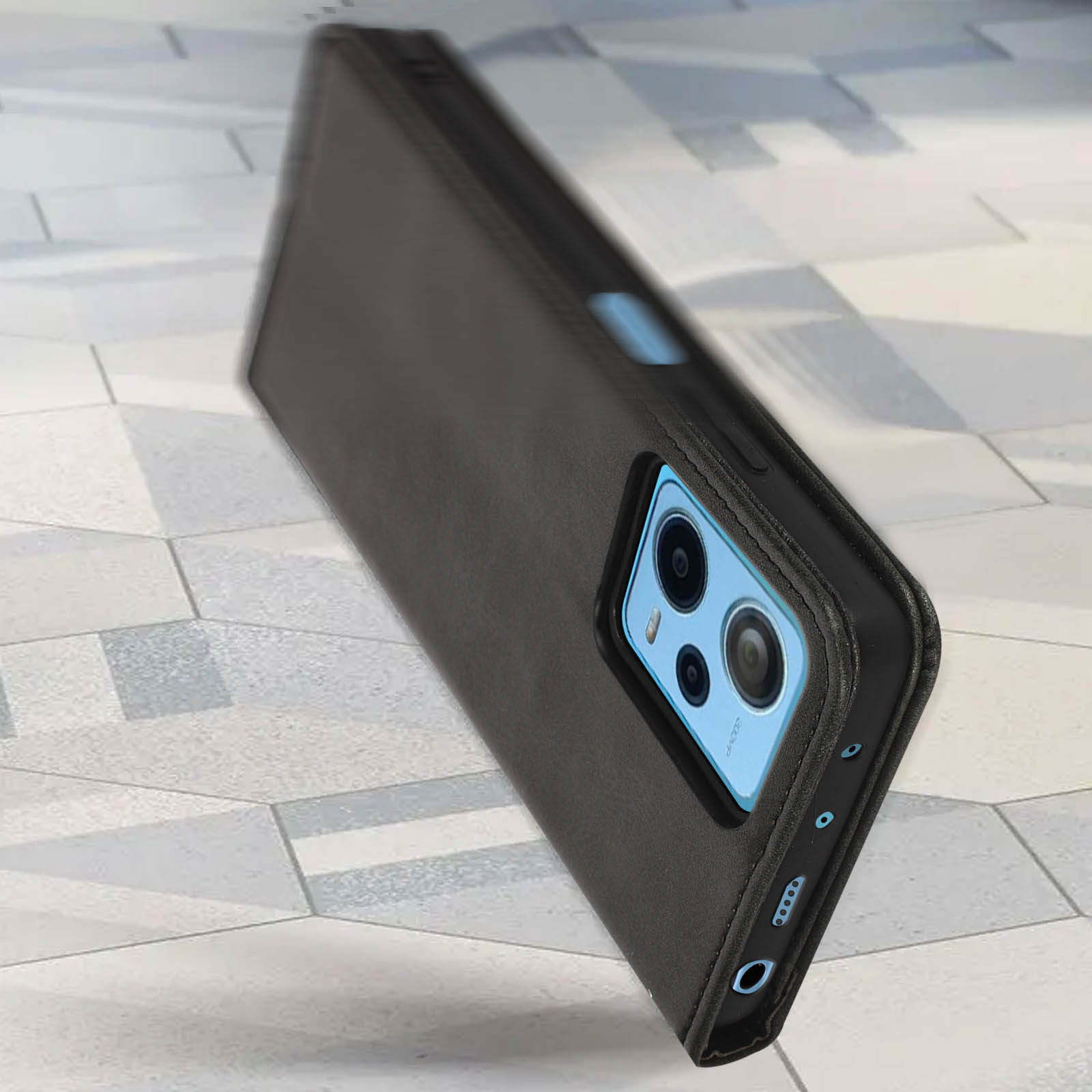 Telefono in custodia in pelle nera con tre fotocamere, appoggiato su una superficie.