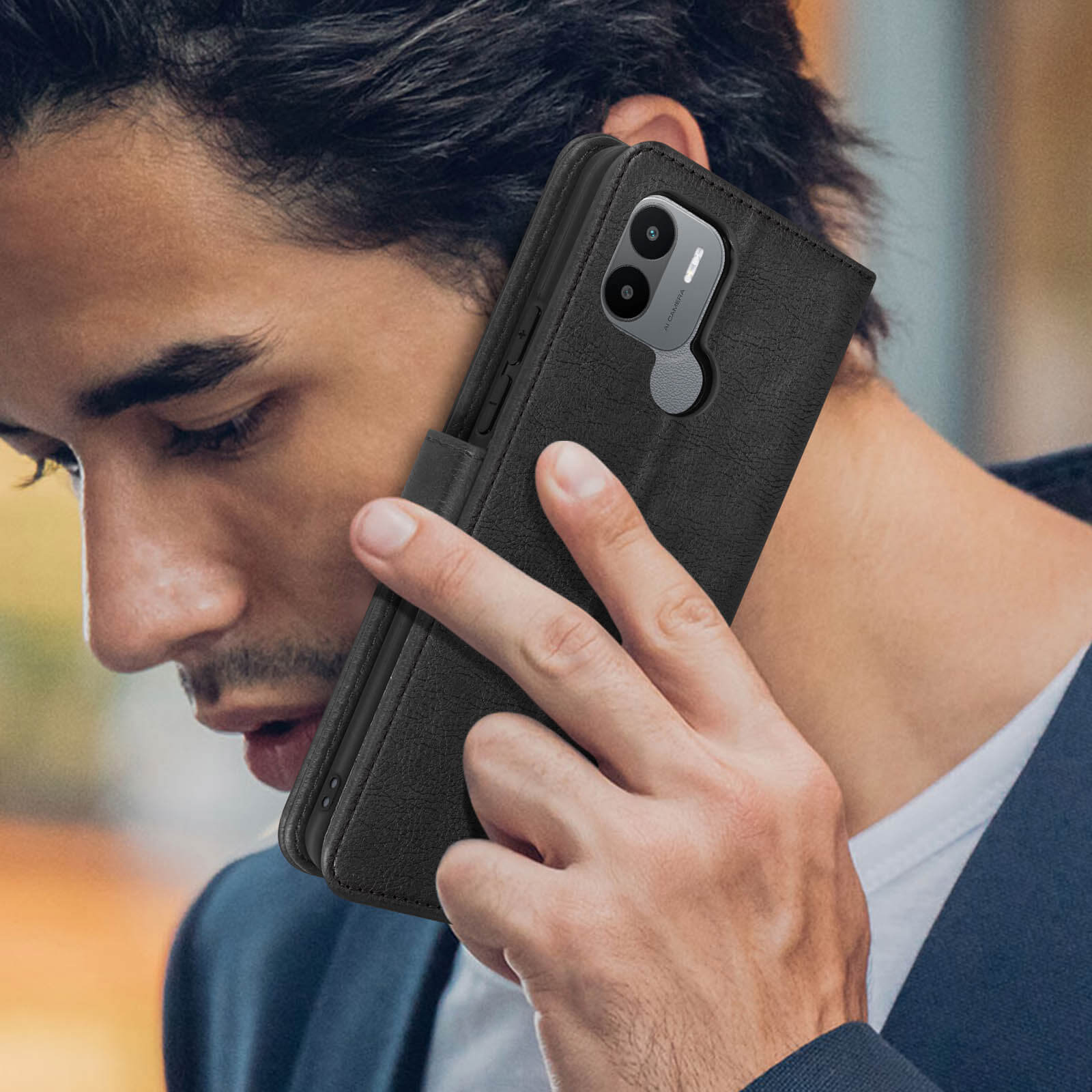 Una persona tiene un telefono nero all'interno di una custodia a portafoglio in pelle nera. Primo piano.