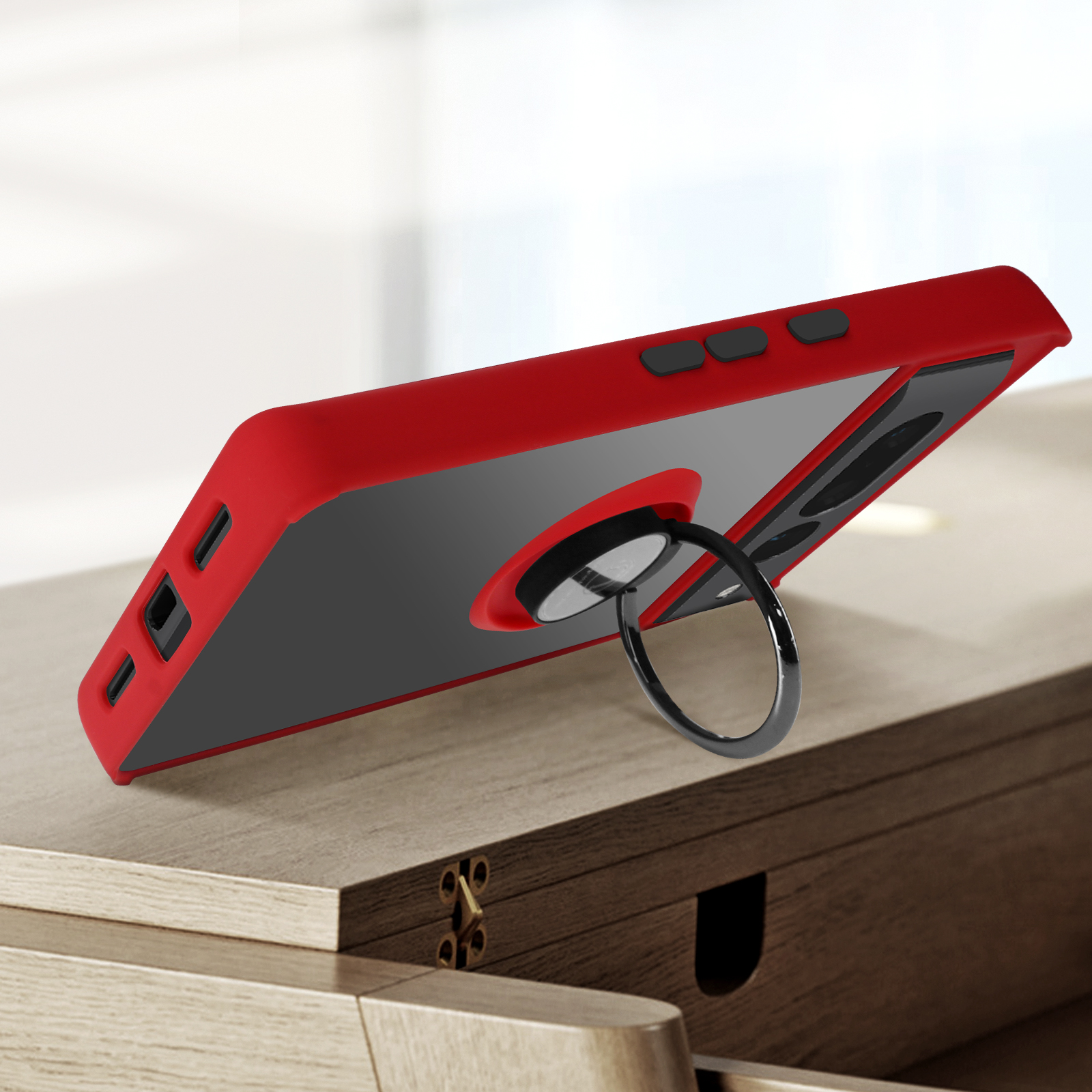 Een rode telefoonhoes met een ringhouder, de telefoon staat op een houten tafel.