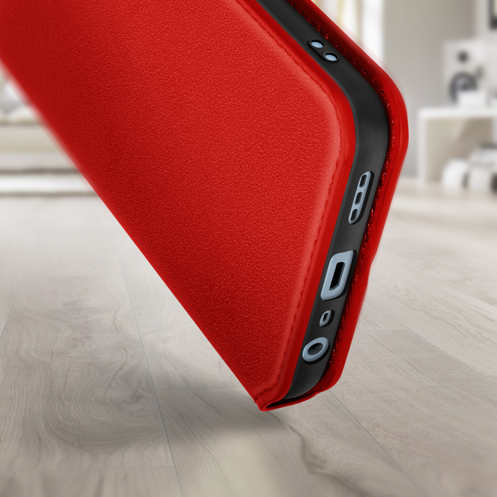 Rode telefoonhoes op een houten oppervlak. De hoes heeft een zwarte rand met uitsparingen voor poorten en knoppen.