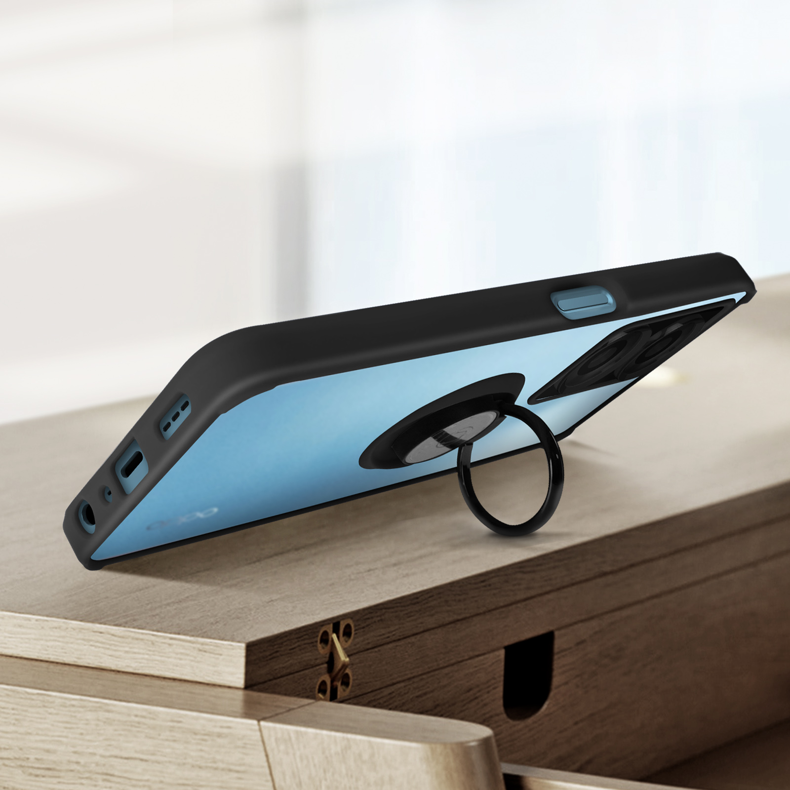 Un telefono nero in una custodia con un supporto ad anello è su una superficie di legno.