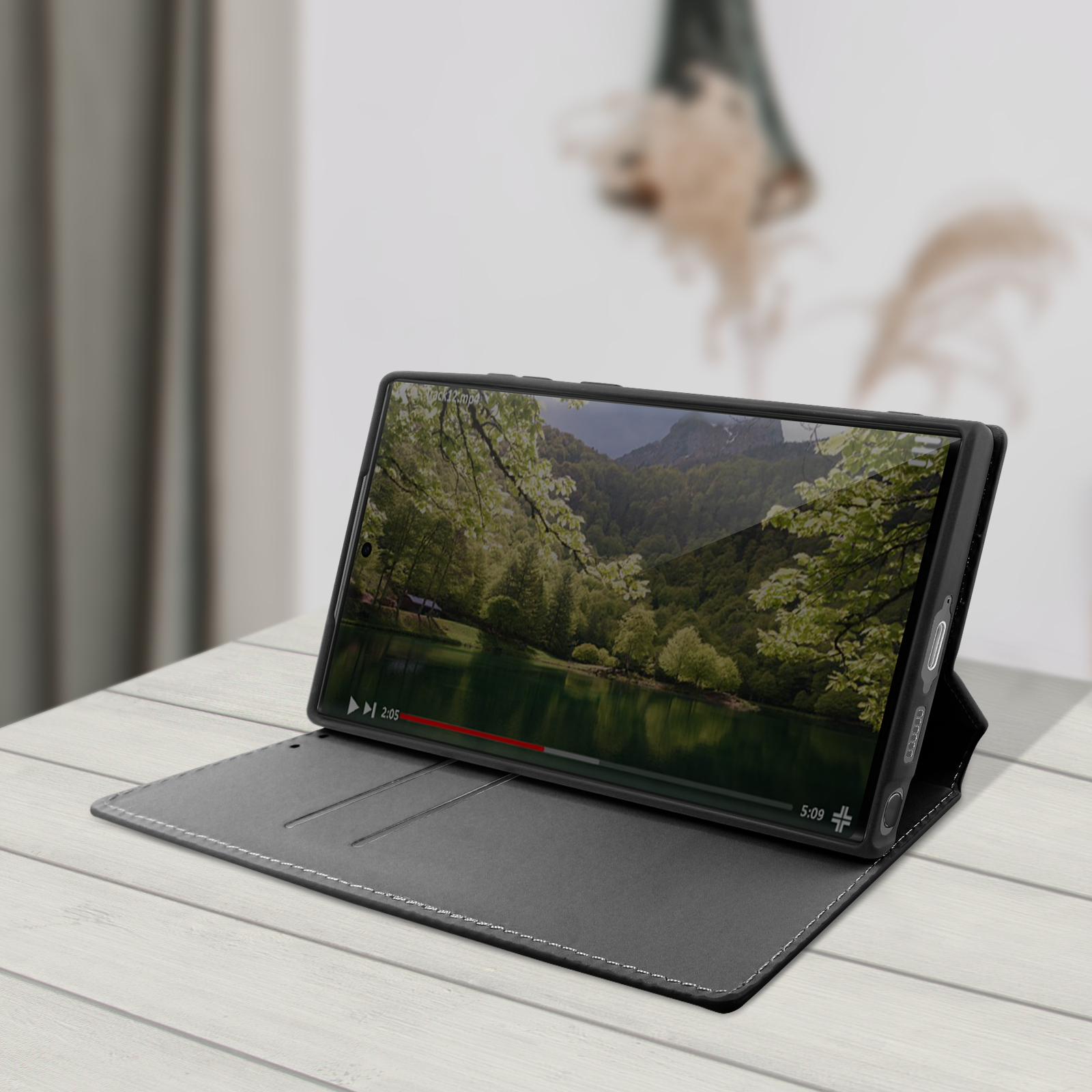 Een telefoon die een video van een landschap toont, op een open, zwarte telefoonhoes.