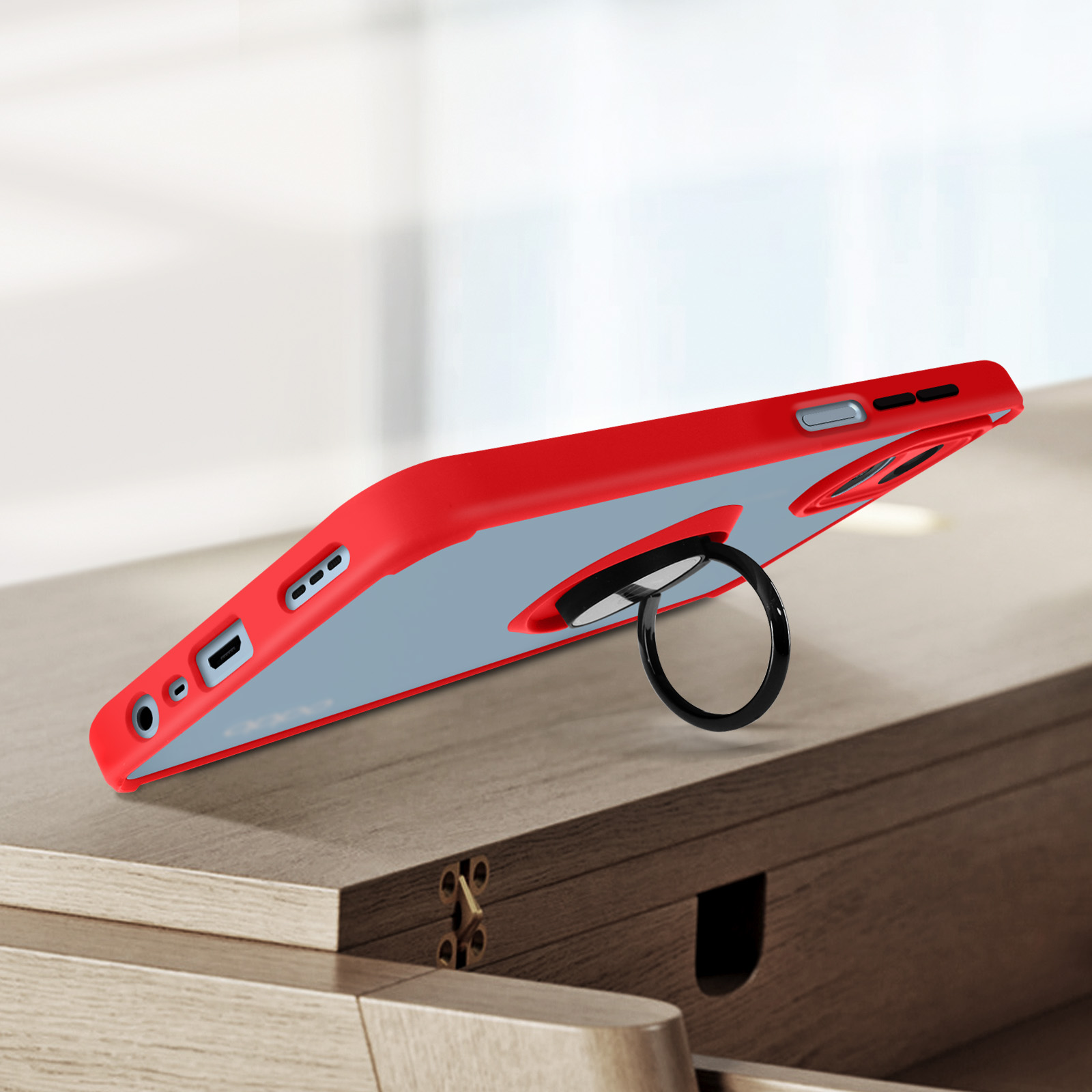 Custodia rossa con supporto ad anello nero, su superficie in legno.