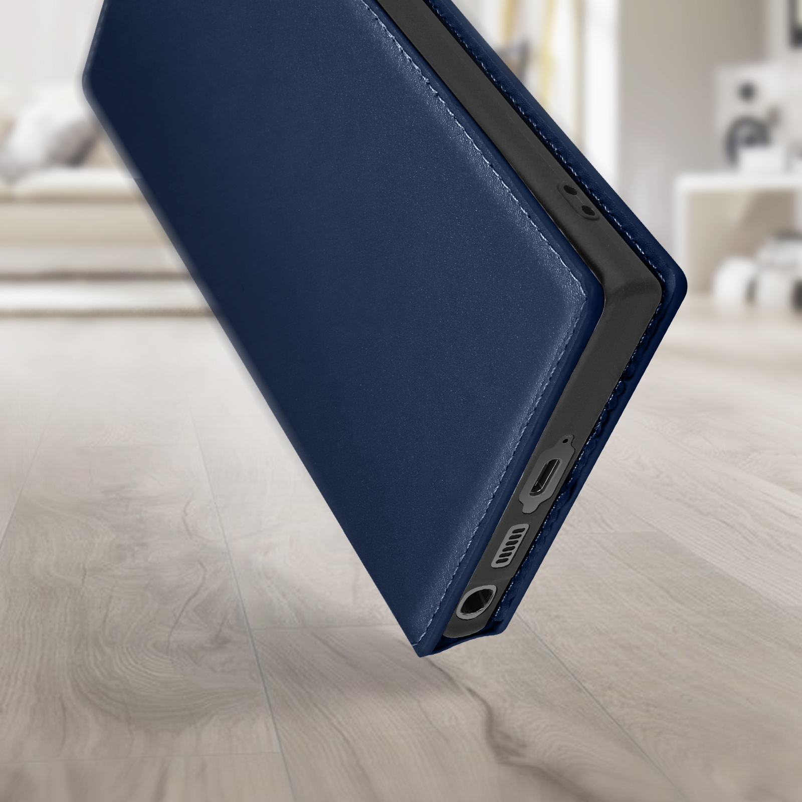Een telefoonhoesje open, marineblauw, liggend op een houten vloer, met een wazige achtergrond.