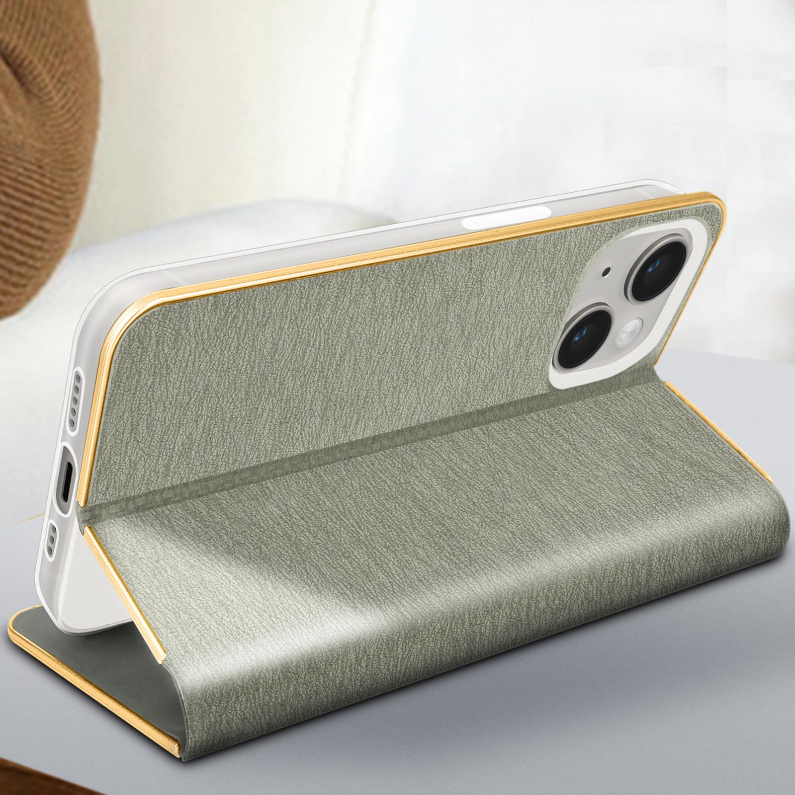 Eine Handyhülle mit goldenem Rand, geöffnet, um das Telefon zu zeigen. Die Hülle ist grau, der Hintergrund unscharf.