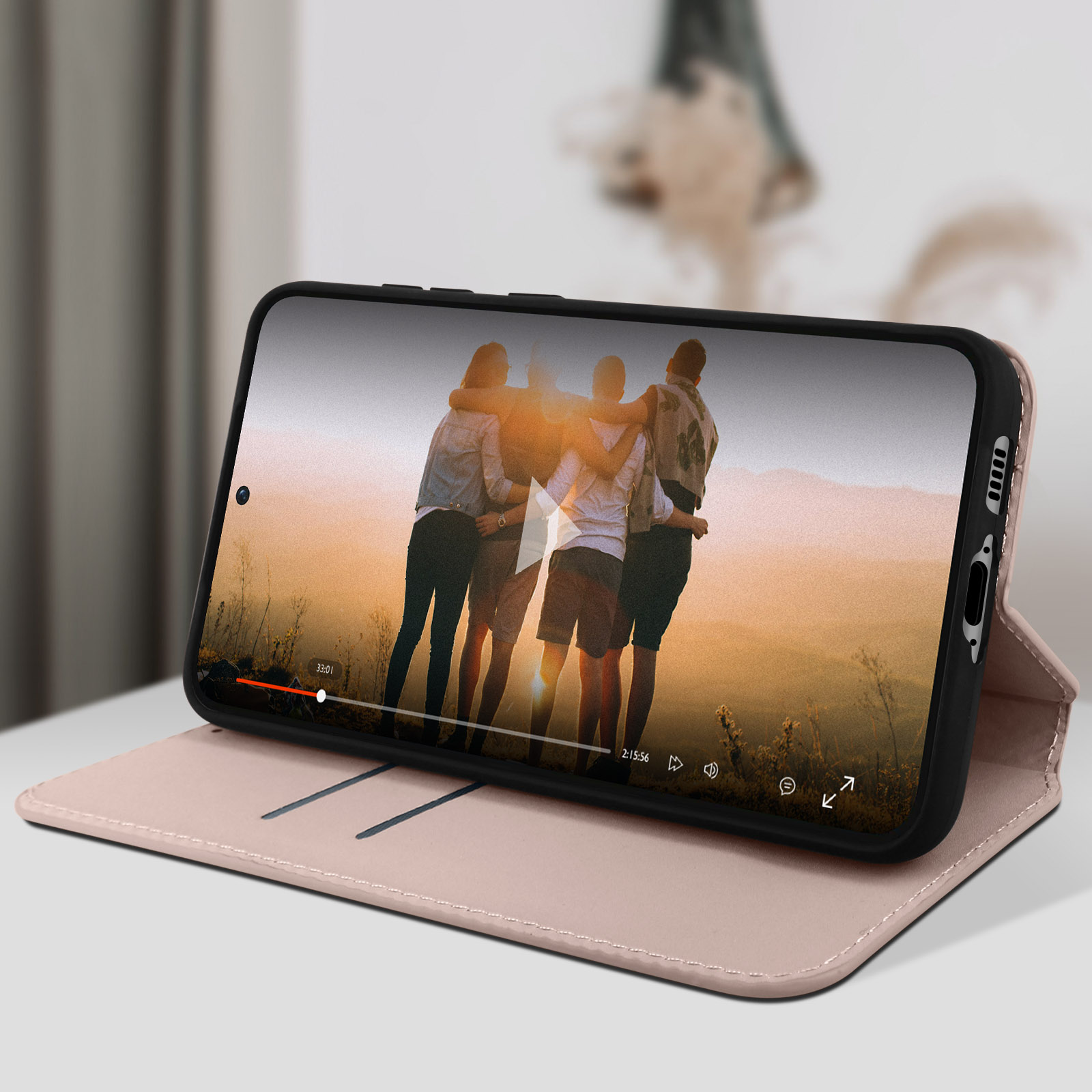 Smartphone dans un étui rose affichant une vidéo de personnes. L'étui est ouvert sur une table.