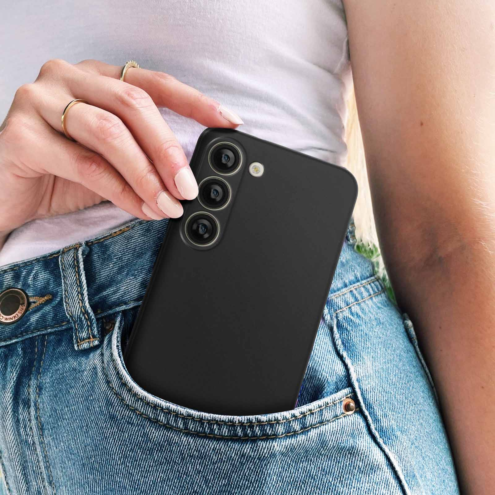 Die Hand einer Frau in einer Jeanstasche mit einem schwarzen Telefon. Der Hintergrund ist unscharf.