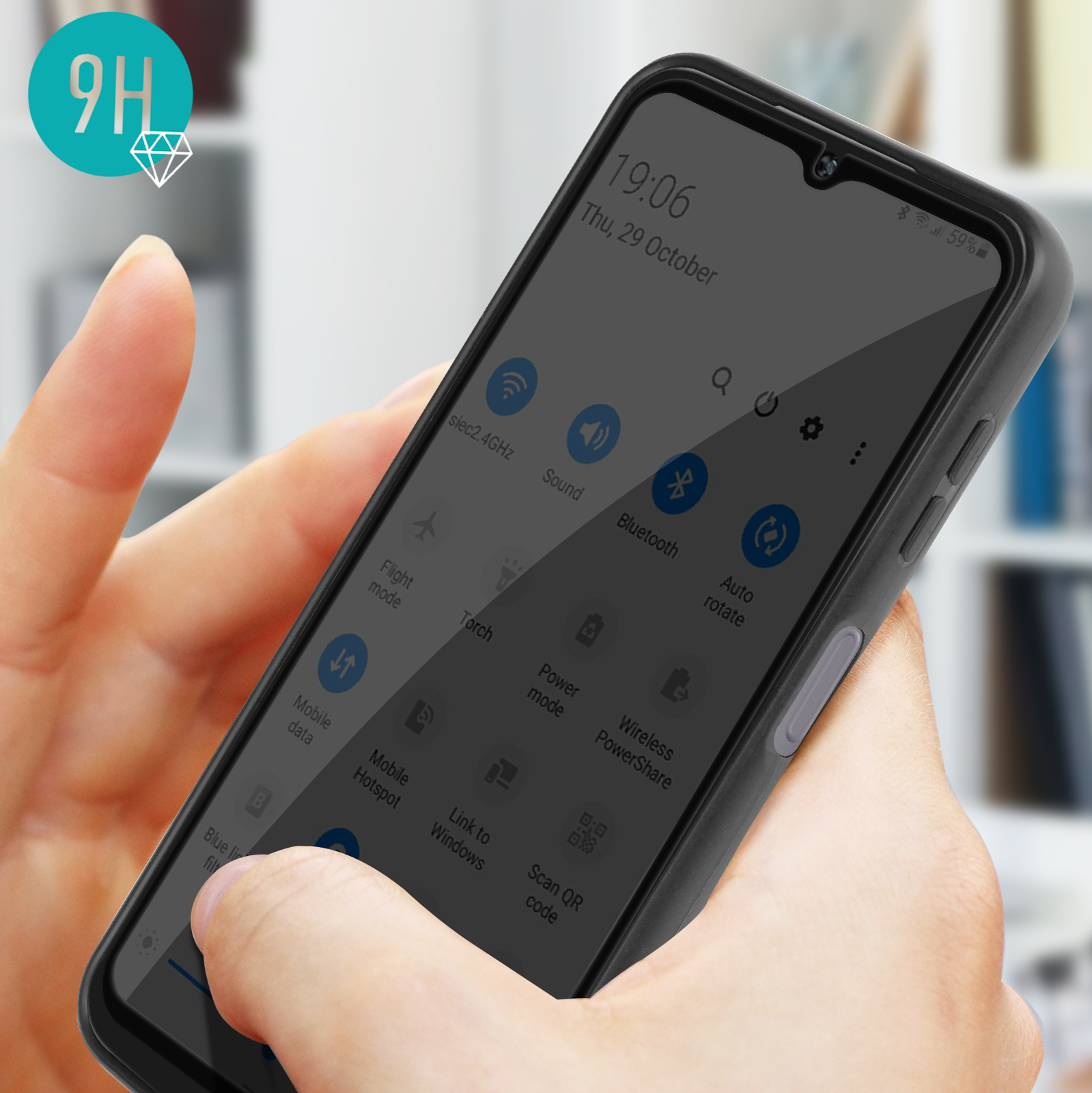 Une main tenant un téléphone avec un protecteur d'écran. Le téléphone affiche le menu des paramètres.