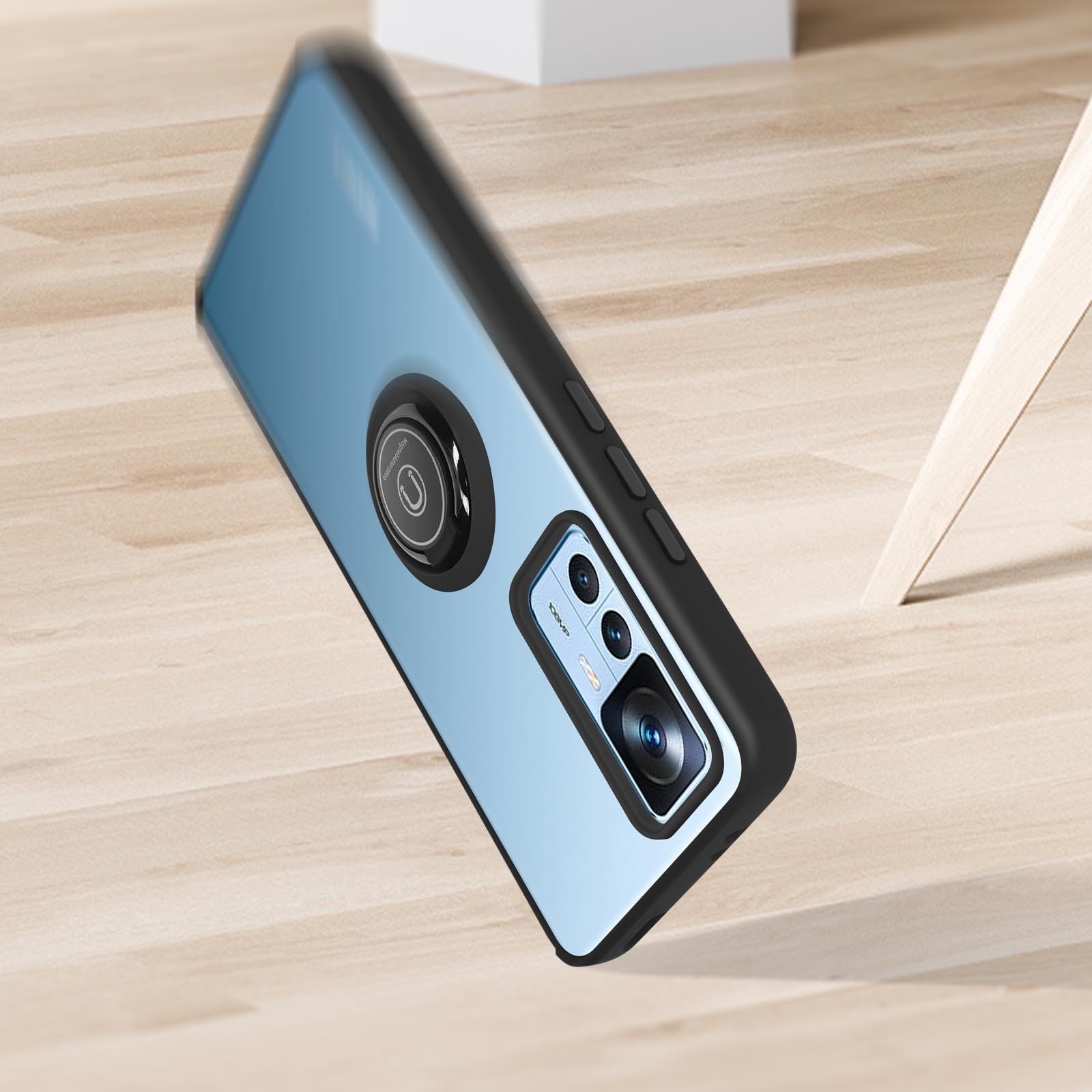 Custodia per telefono con supporto ad anello su superficie in legno. Custodia blu chiaro con anello nero.