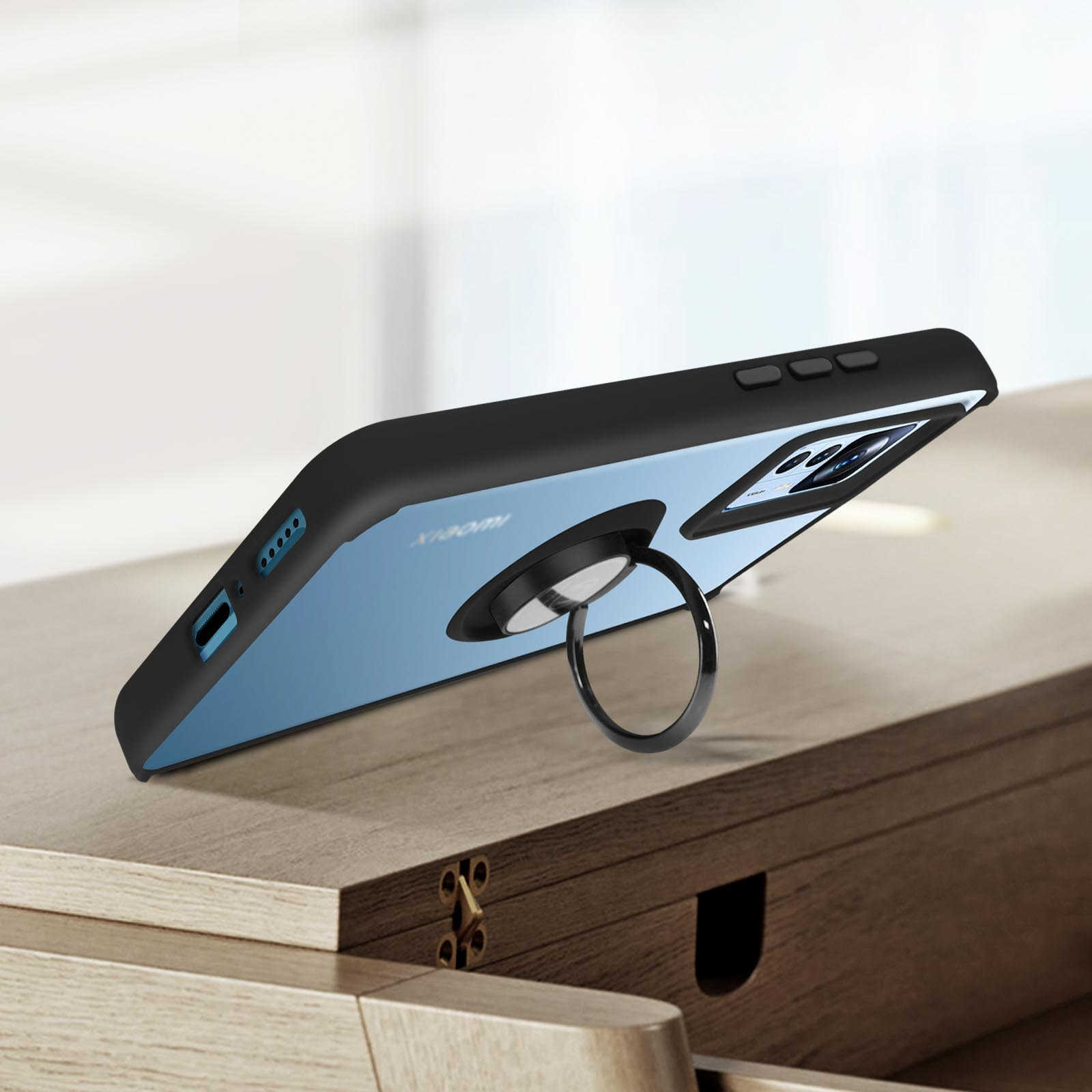 Telefono nero, porta anello, appoggiato su una superficie di legno. Schienale blu visibile. Primo piano.