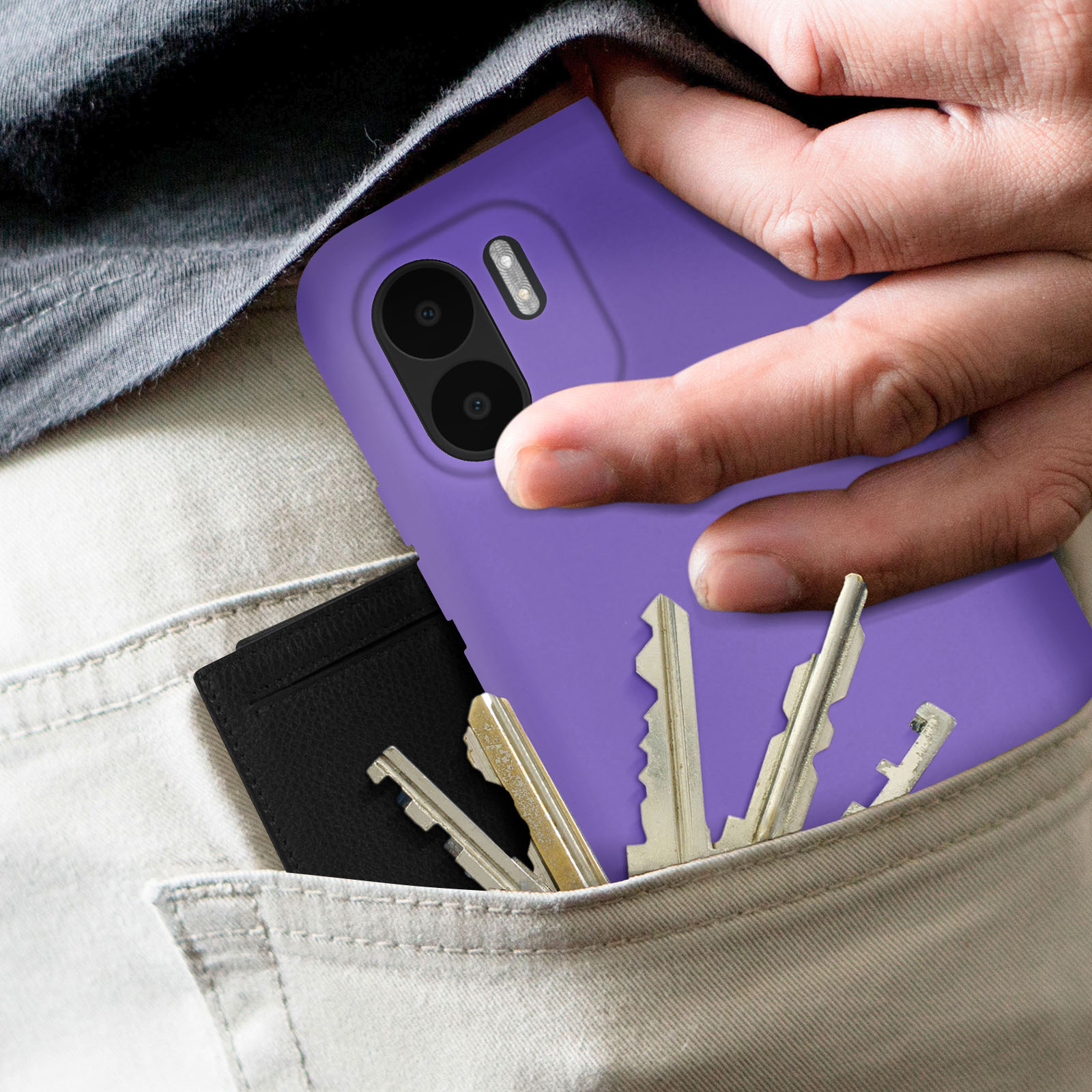 Telefono viola in tasca con chiavi e portafoglio nero, con pantaloni beige visibili.