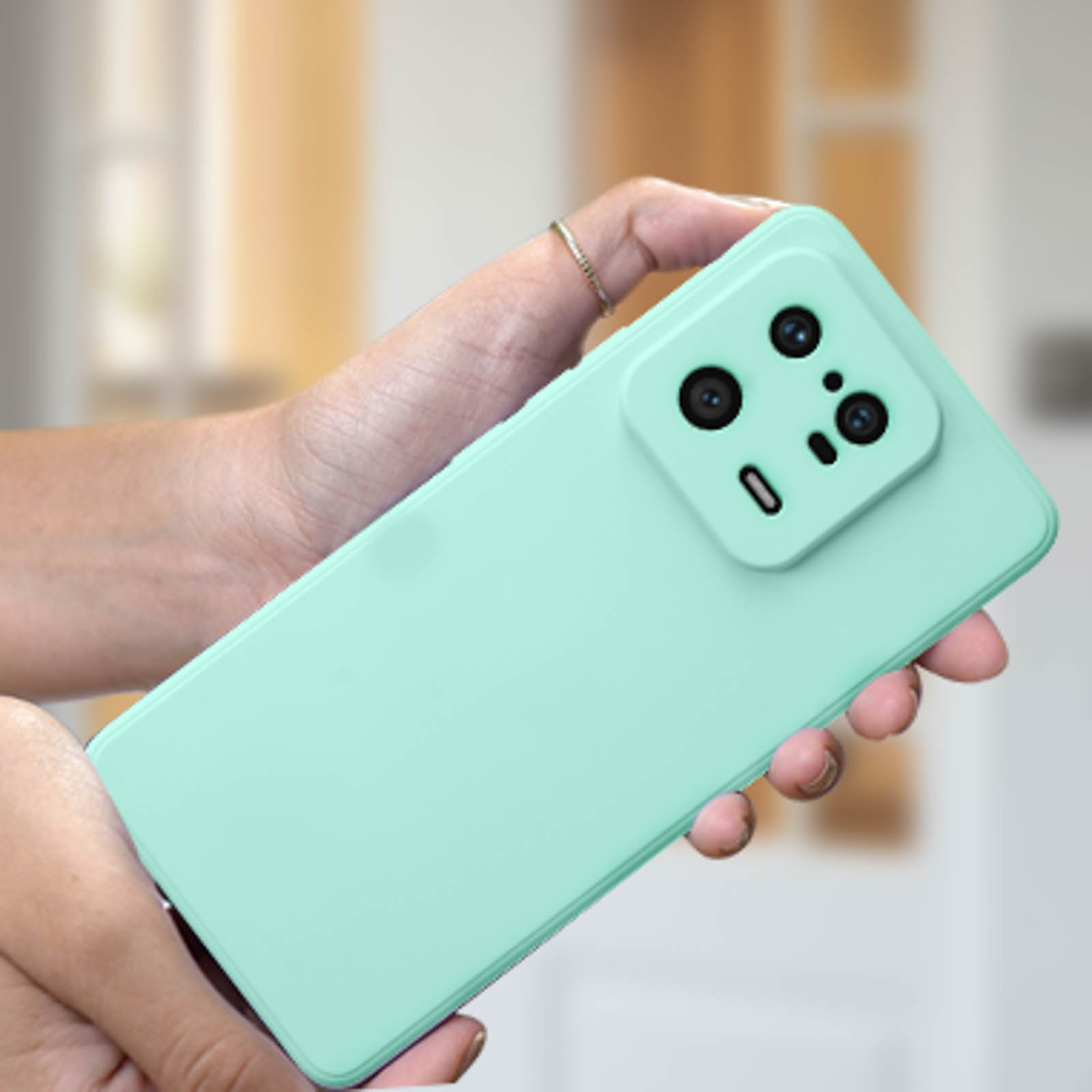 Mani che tengono una custodia verde menta con un telefono dentro.