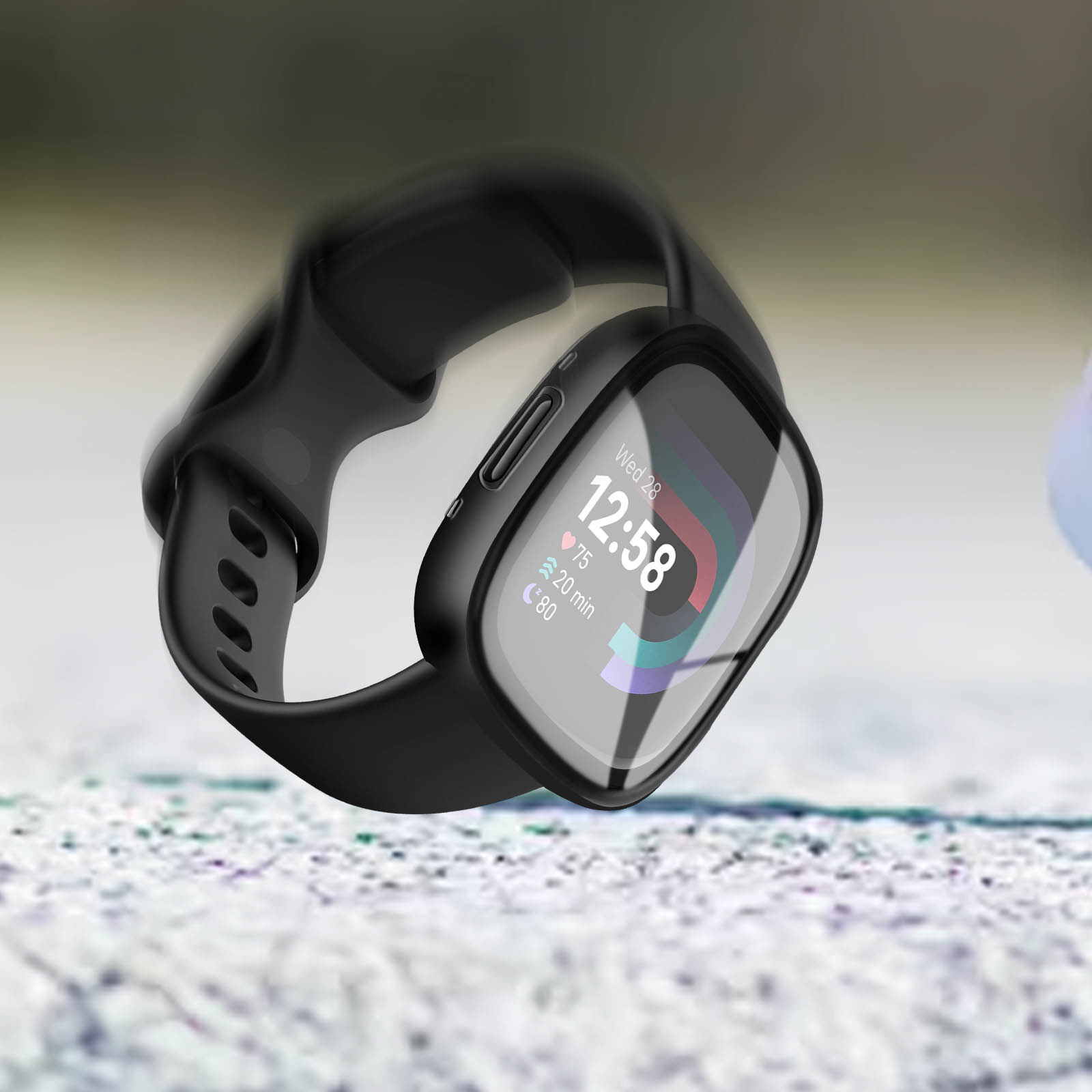 Eine schwarze Smartwatch mit schwarzem Armband wird vor verschwommenem Hintergrund getragen.