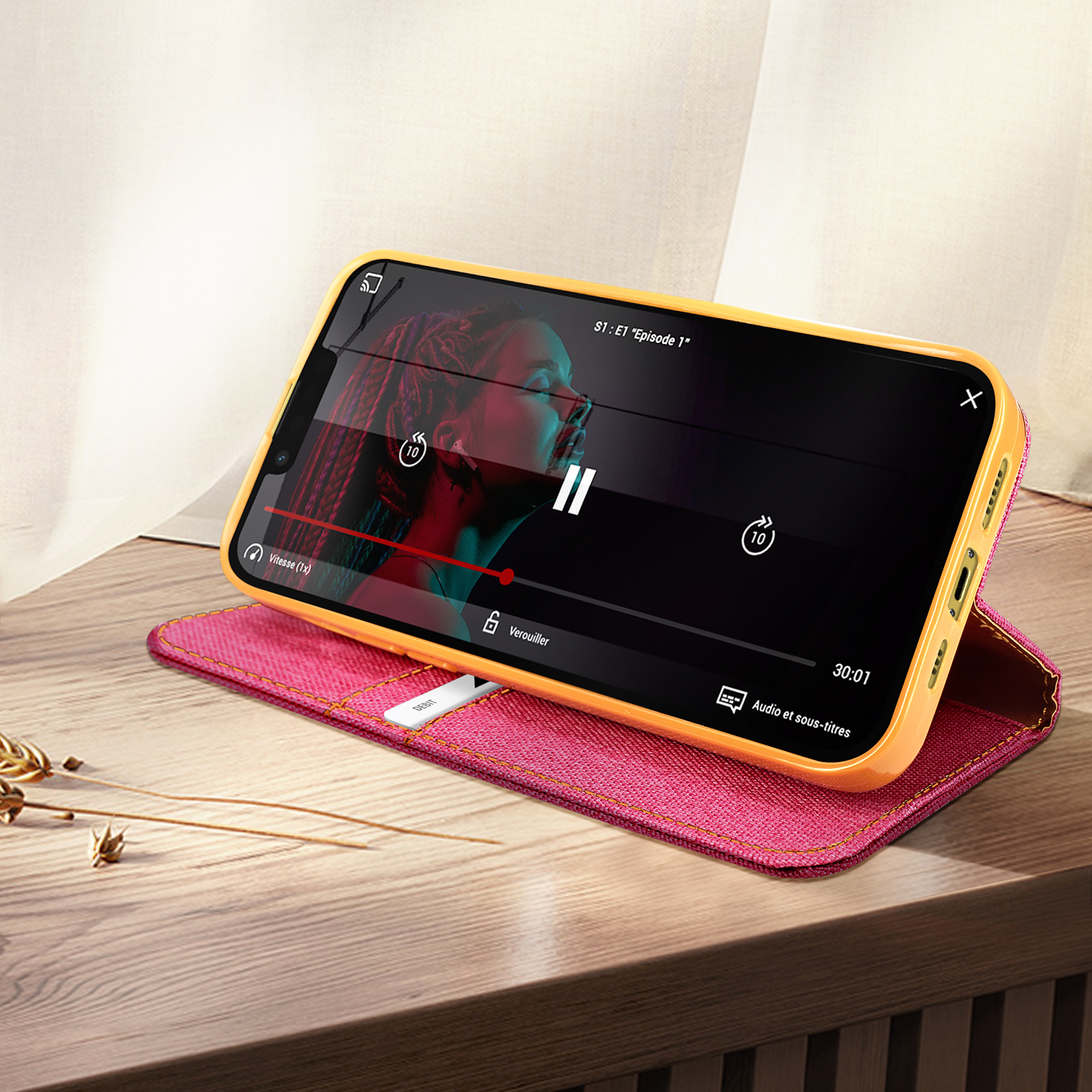 Telefono con video su custodia rosa. Tavolo in legno.