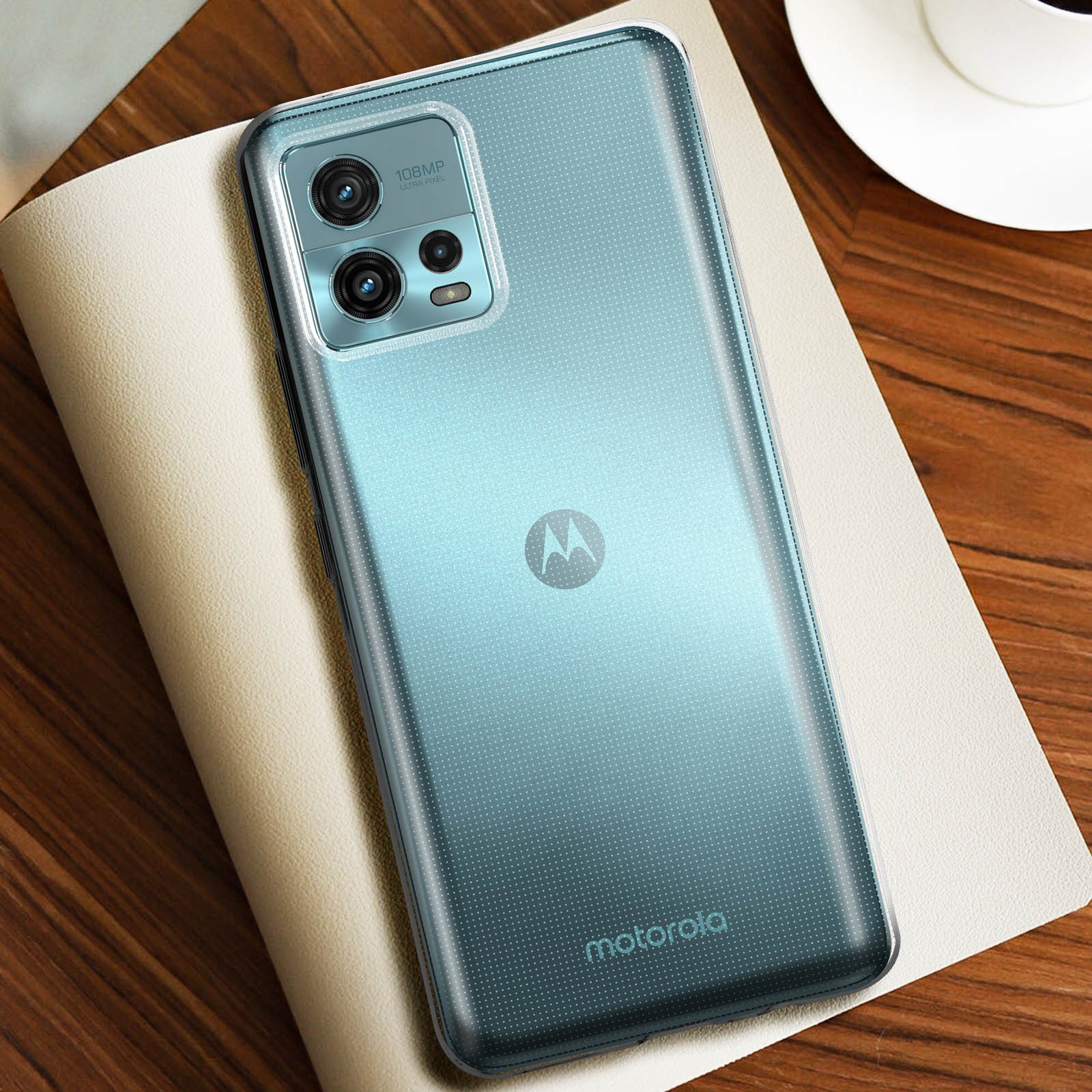 Un telefono blu con una custodia trasparente su un taccuino e una tazza.