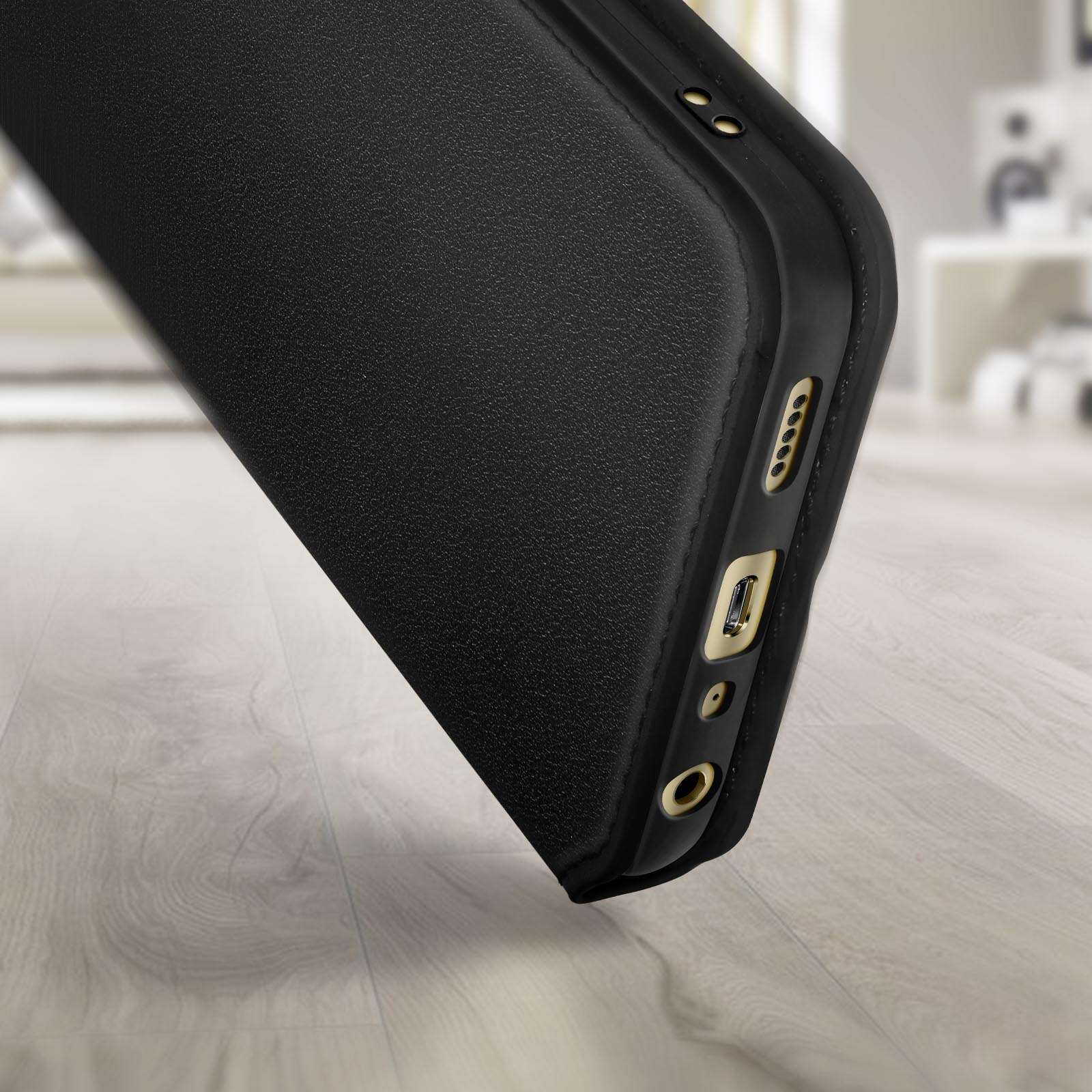 Primo piano di una custodia per telefono nera con dettagli dorati. La custodia è su una superficie di legno.