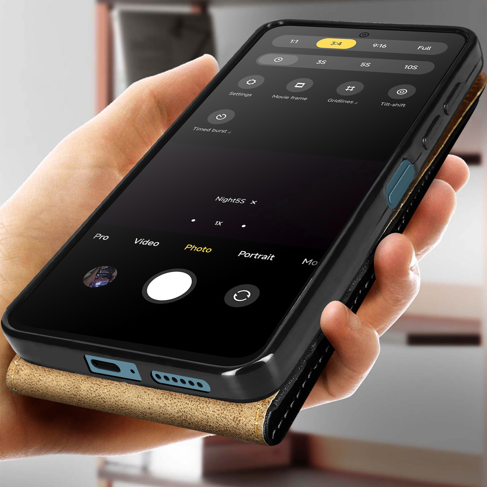 Une main tenant un téléphone avec les paramètres de l'appareil photo visibles, avec un étui en cuir.