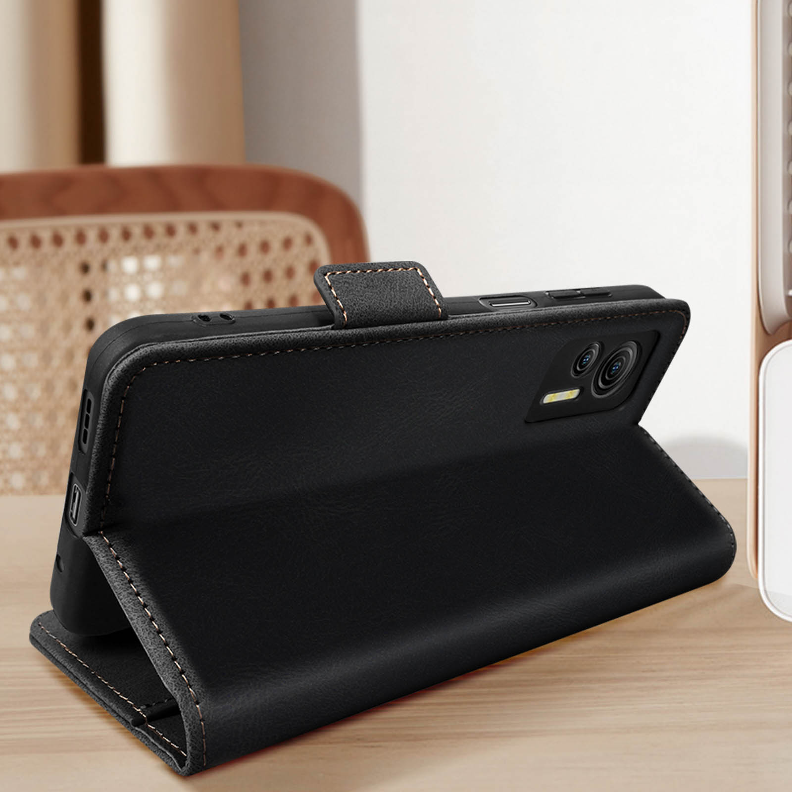 Custodia per telefono in pelle nera aperta, che mostra il telefono all'interno. Tavolo e sfondo in legno marrone.