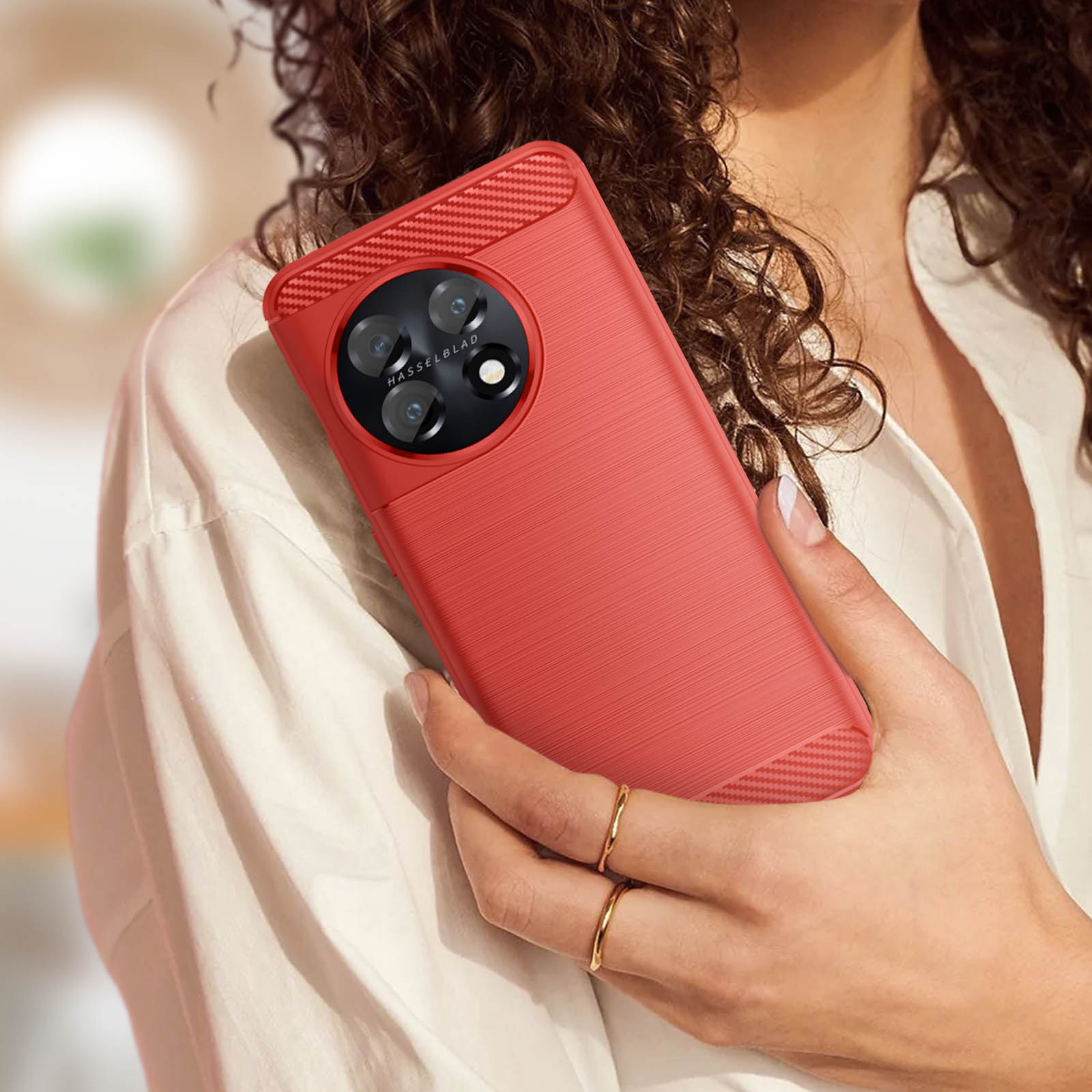 Una donna tiene in mano un telefono rosso con una custodia rossa. La custodia ha un retro strutturato e un rilievo della fotocamera.