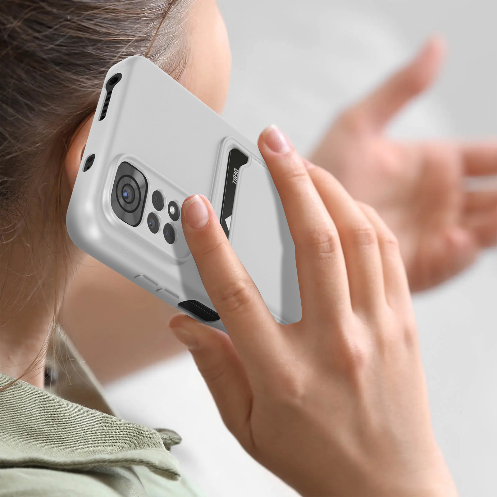 Una donna tiene un telefono con custodia bianca all'orecchio. Il telefono ha una fotocamera.