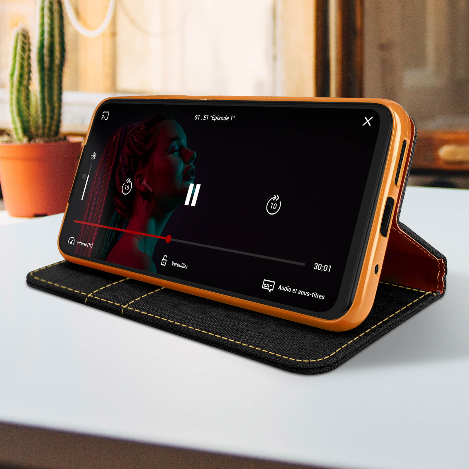 Telefono in una custodia arancione che riproduce un video. La custodia è su un tavolo, con un design nero e giallo.
