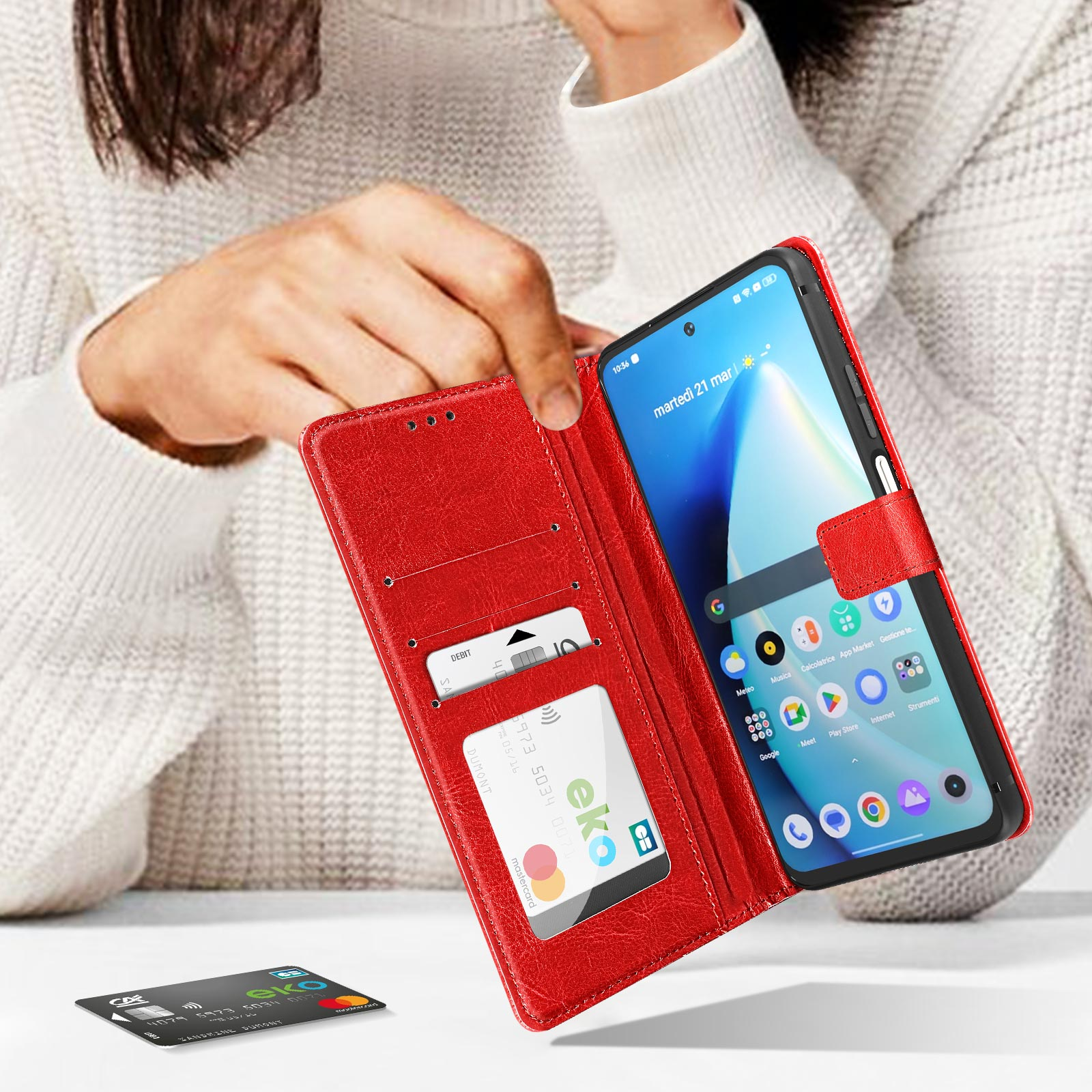 Eine Person, die ein Telefon in einer roten Handyhülle hält und eine Debitkarte und den Bildschirm zeigt.