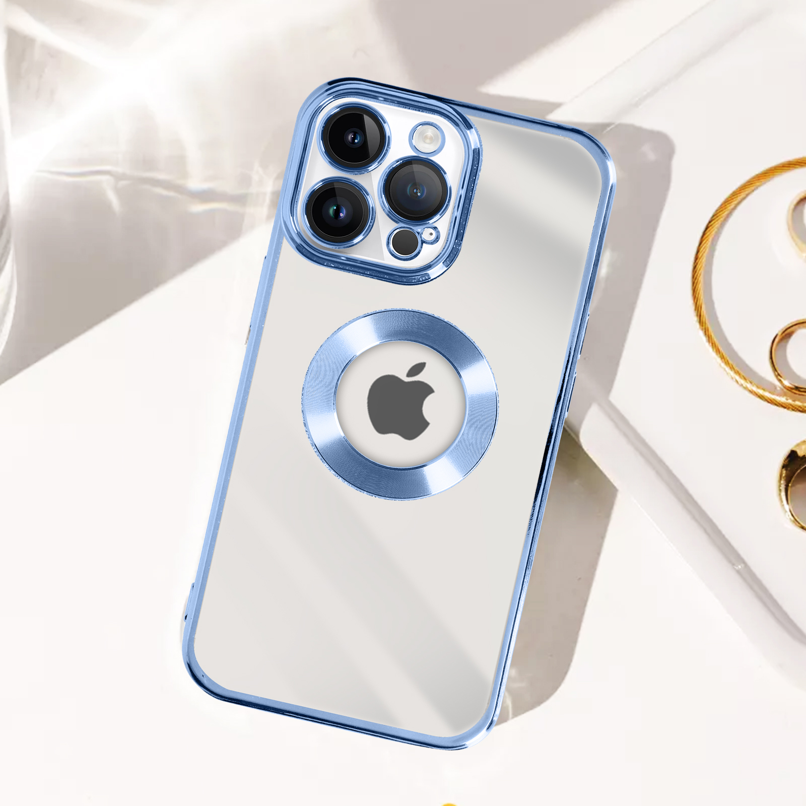 iPhone in custodia trasparente con bordi blu, logo e anello Apple argentati, su superficie bianca.
