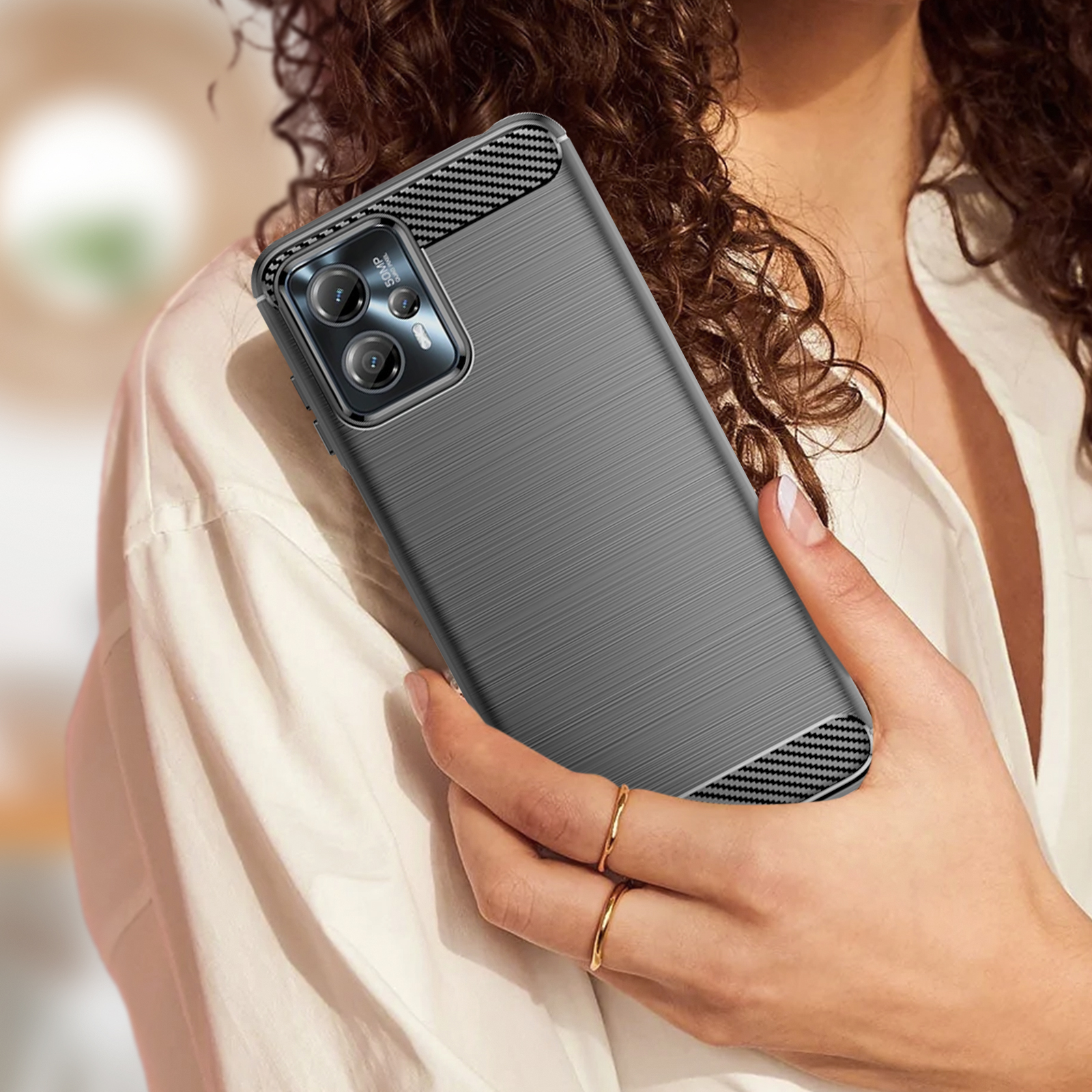 Mano di donna che tiene telefono grigio con custodia strutturata. Custodia con design in fibra di carbonio.
