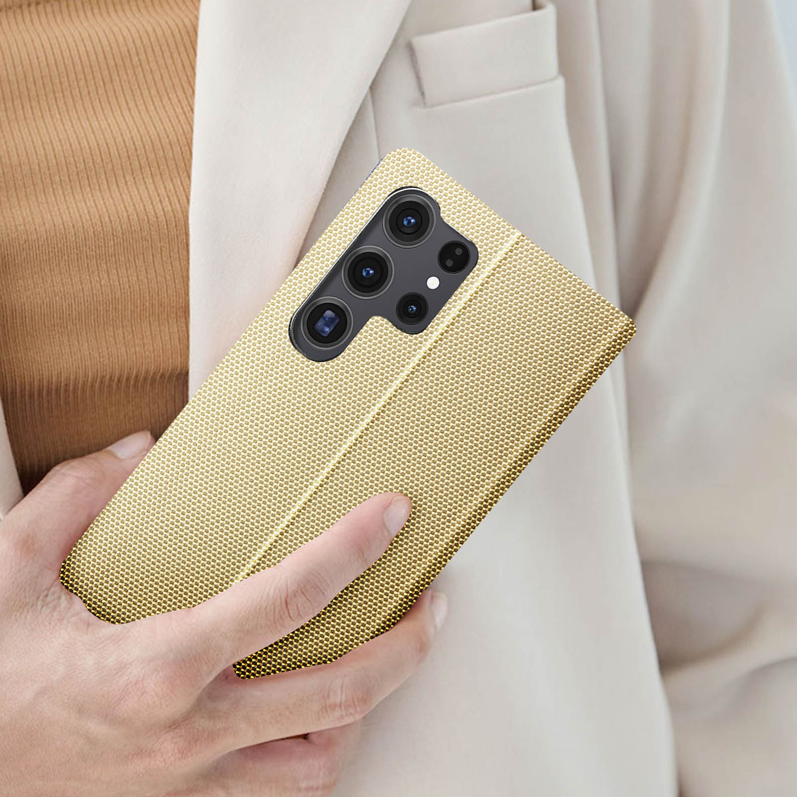 Una custodia per telefono dorata su un telefono, tenuta da una persona con una giacca di colore chiaro.