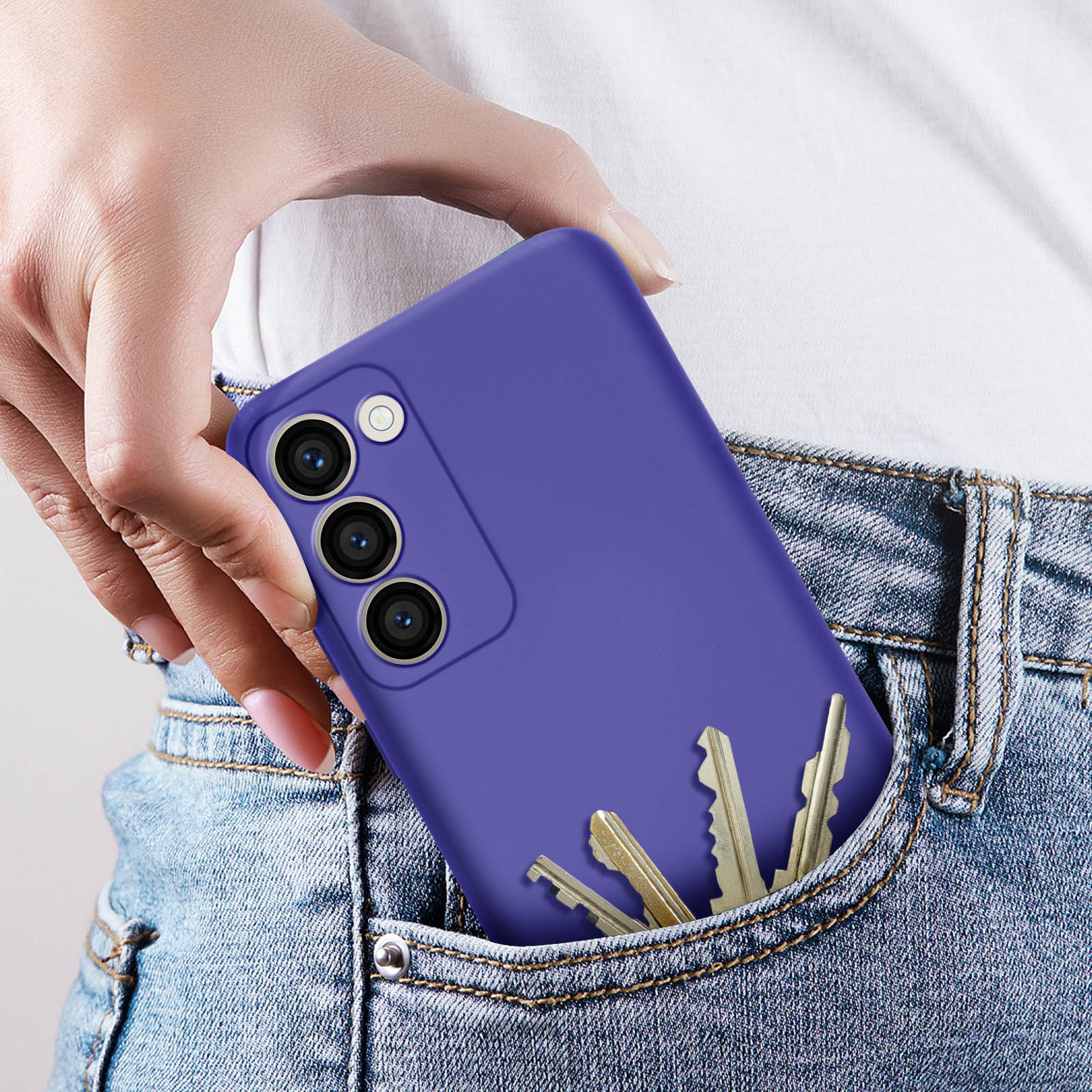Telefono viola in tasca di jeans con chiavi. Una mano tiene un telefono. Jeans blu.