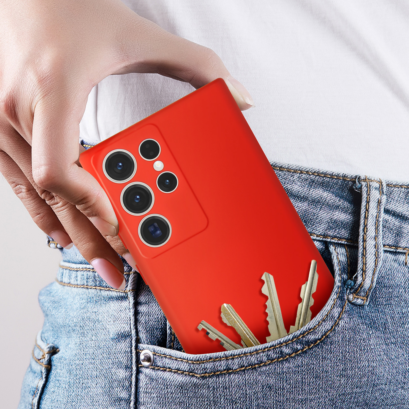 Un telefono rosso in tasca con chiavi. La tasca è su jeans blu.