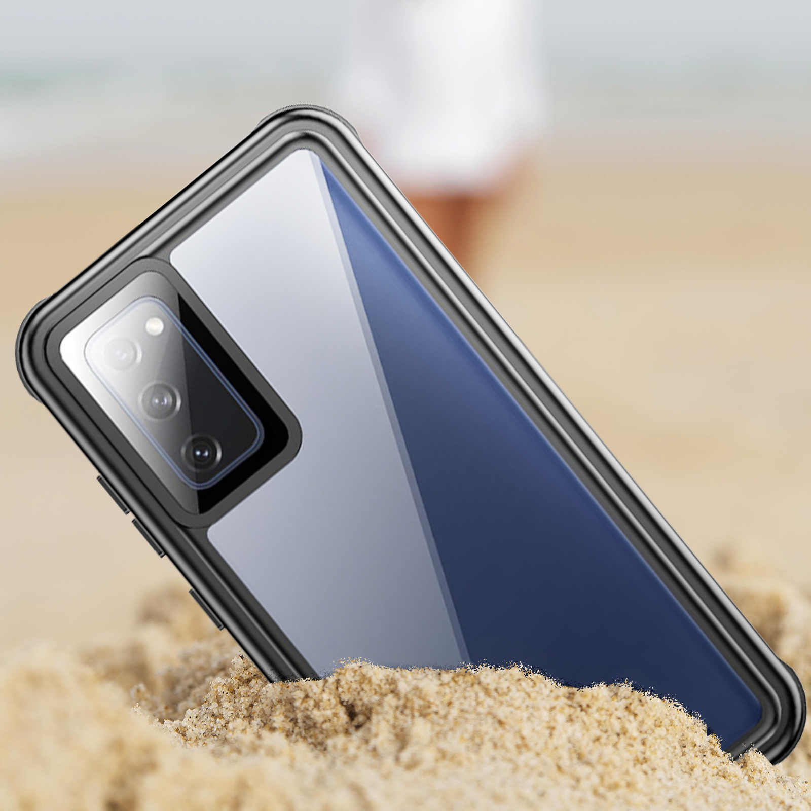 Telefoonhoesje op zand. Zwarte hoes met zichtbare camera. Achtergrond is strand en wazige persoon.