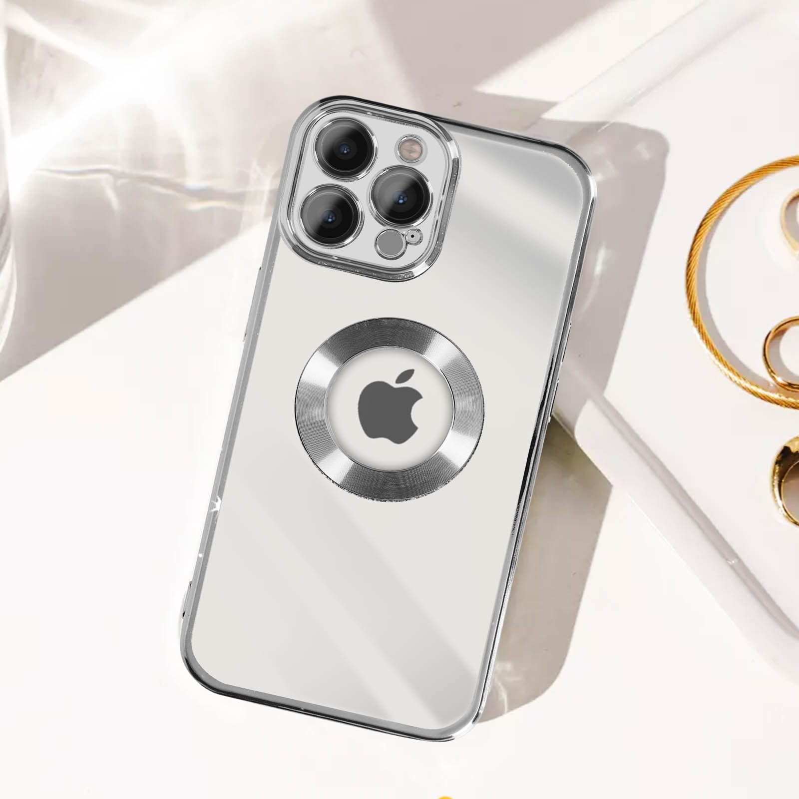 Custodia trasparente con logo Apple su superficie bianca con bracciale d'oro.