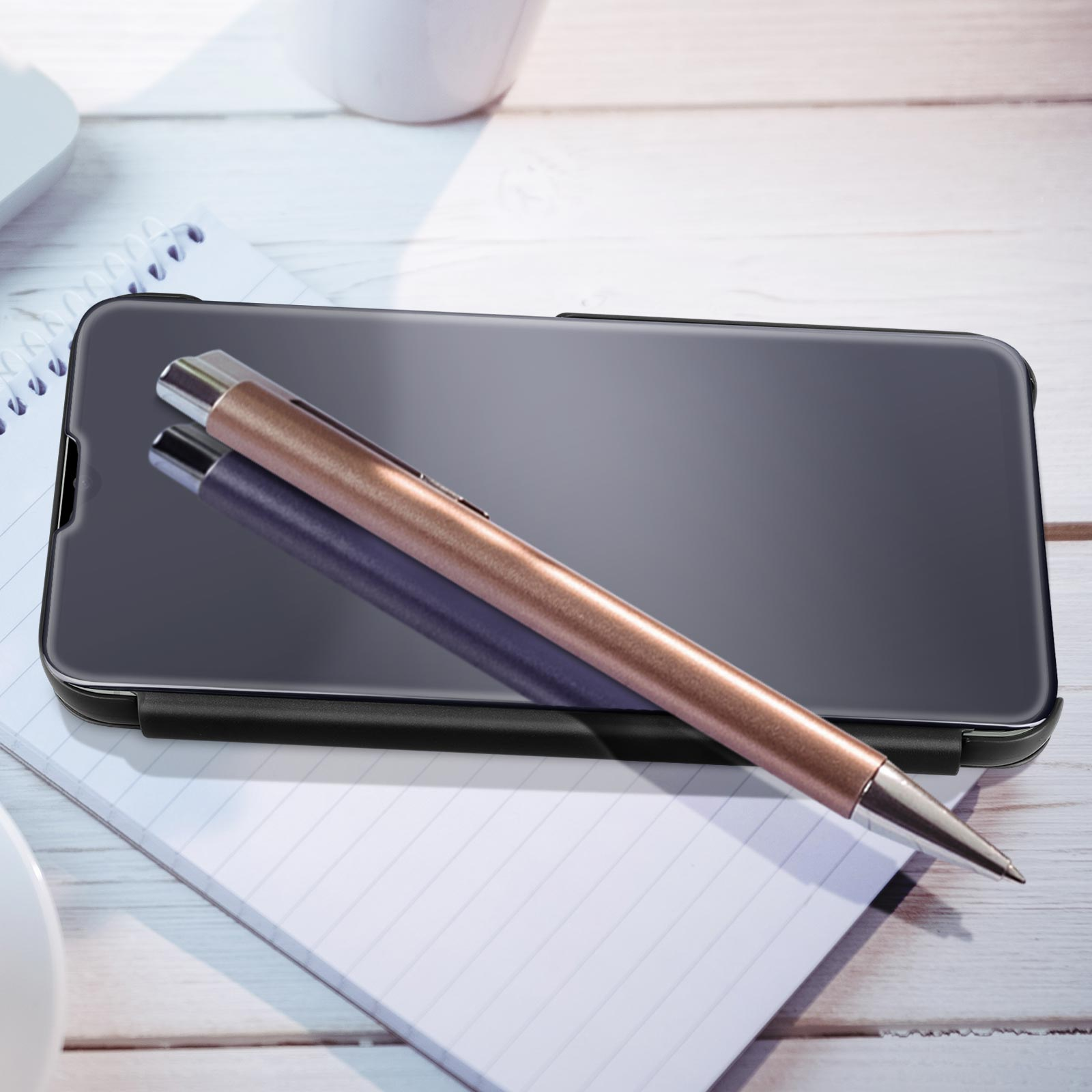 Telefono con penna su un quaderno, su una scrivania in legno.