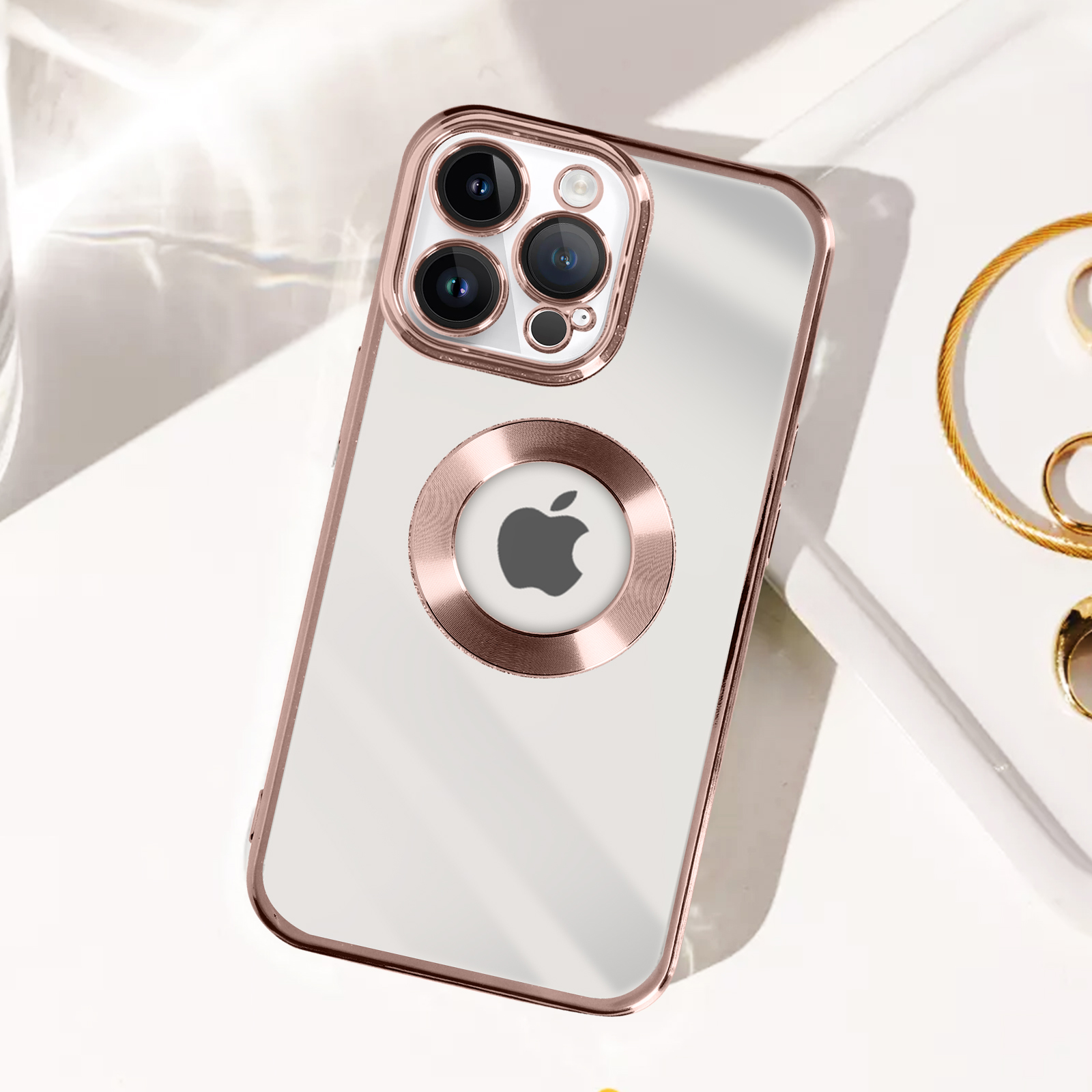 Una custodia trasparente con dettagli oro rosa, che mostra un telefono Apple. Gioielli di lato.