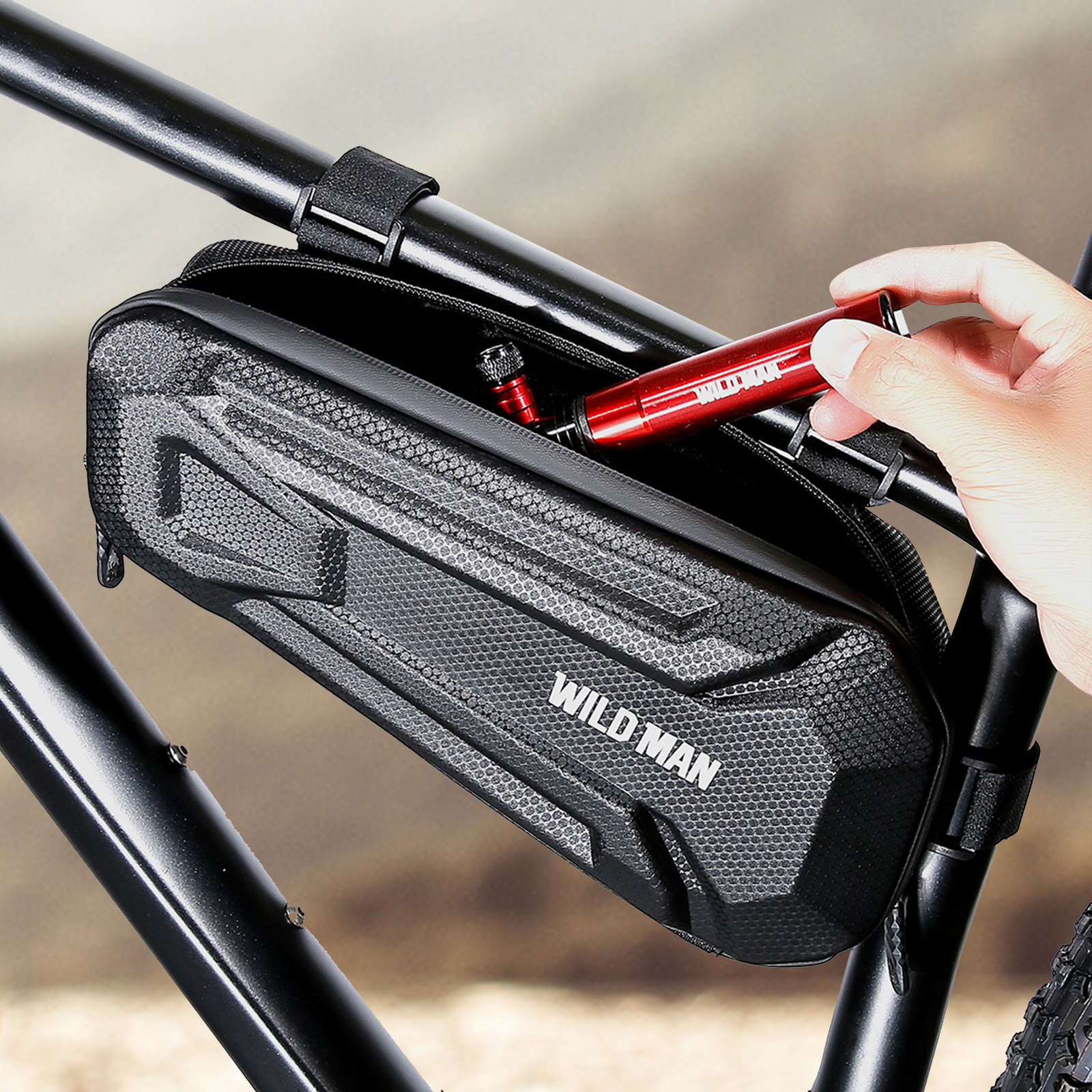 Eine Hand steckt eine rote Pumpe in eine offene schwarze Fahrradtasche, die an einem Fahrrad befestigt ist.