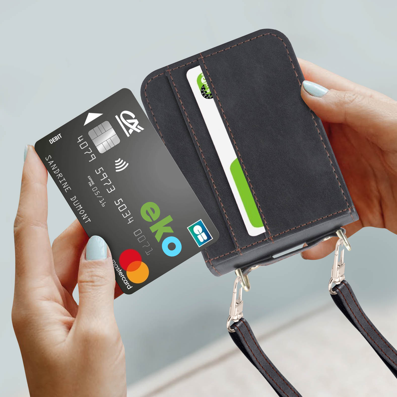 Mani che tengono una custodia nera per telefono con carta di credito e carta e-wallet.