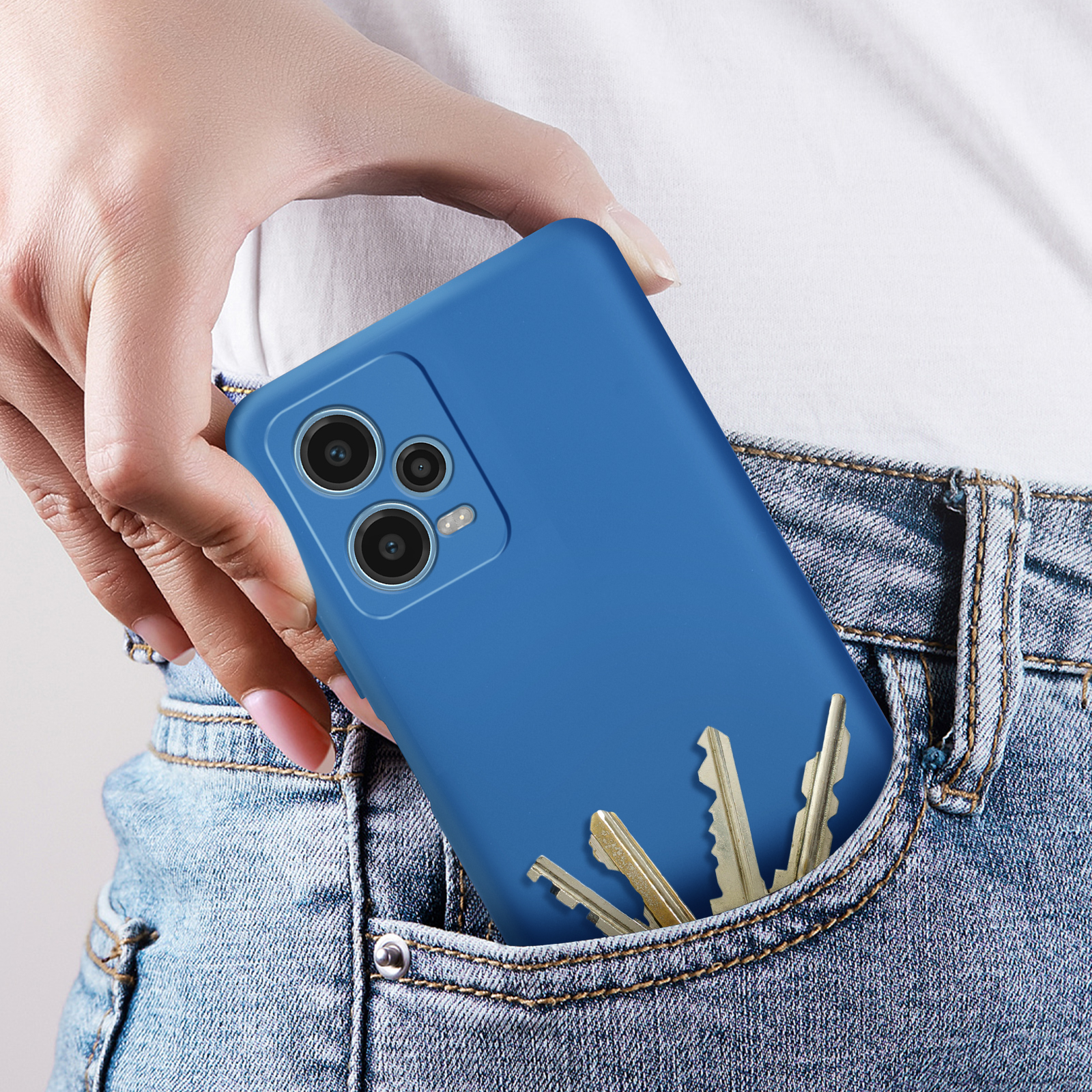 Una custodia per telefono blu in una tasca di jeans con chiavi. Il telefono ha fotocamere sul retro.