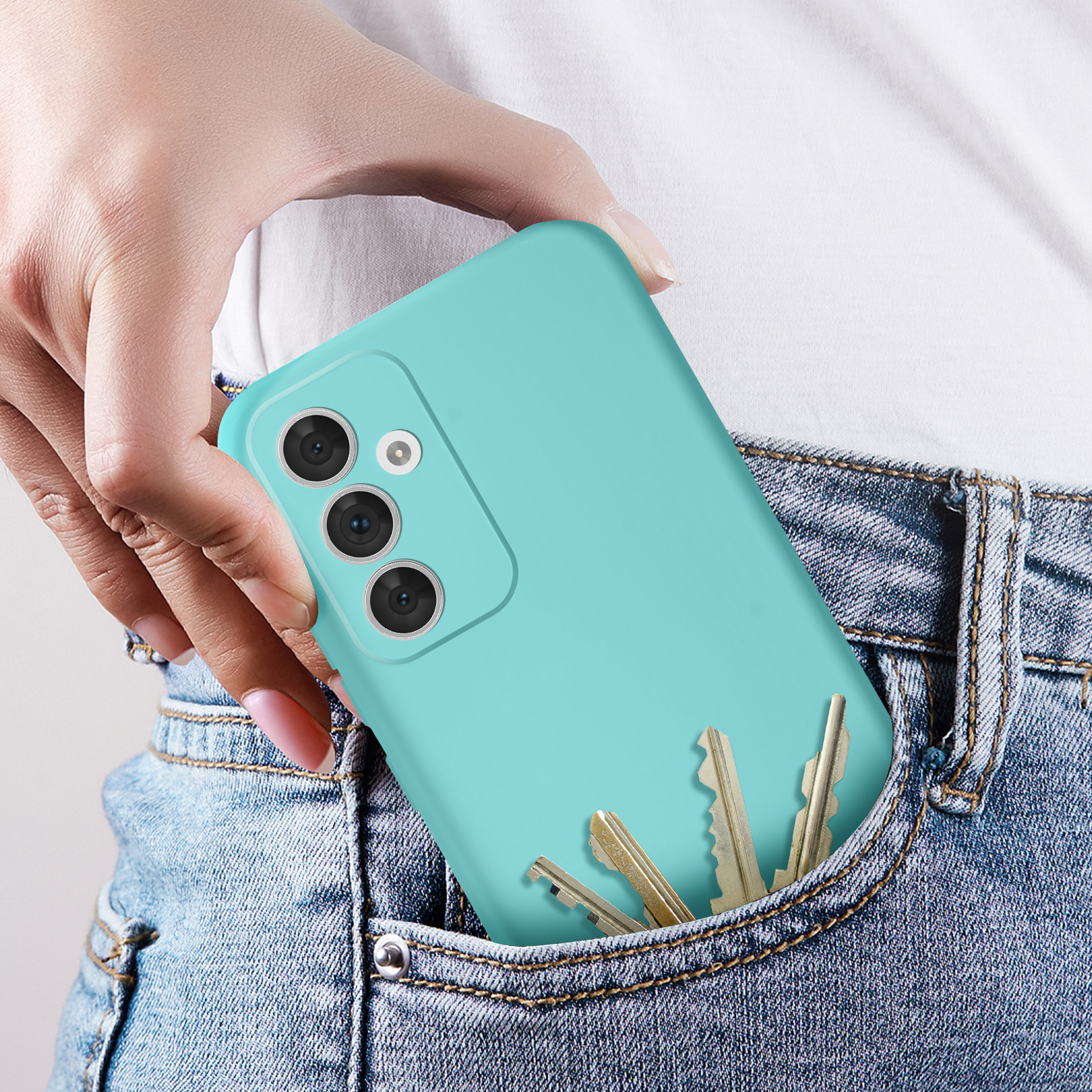 Una mano che tiene un telefono turchese con una custodia turchese in una tasca di jeans, con chiavi all'interno.